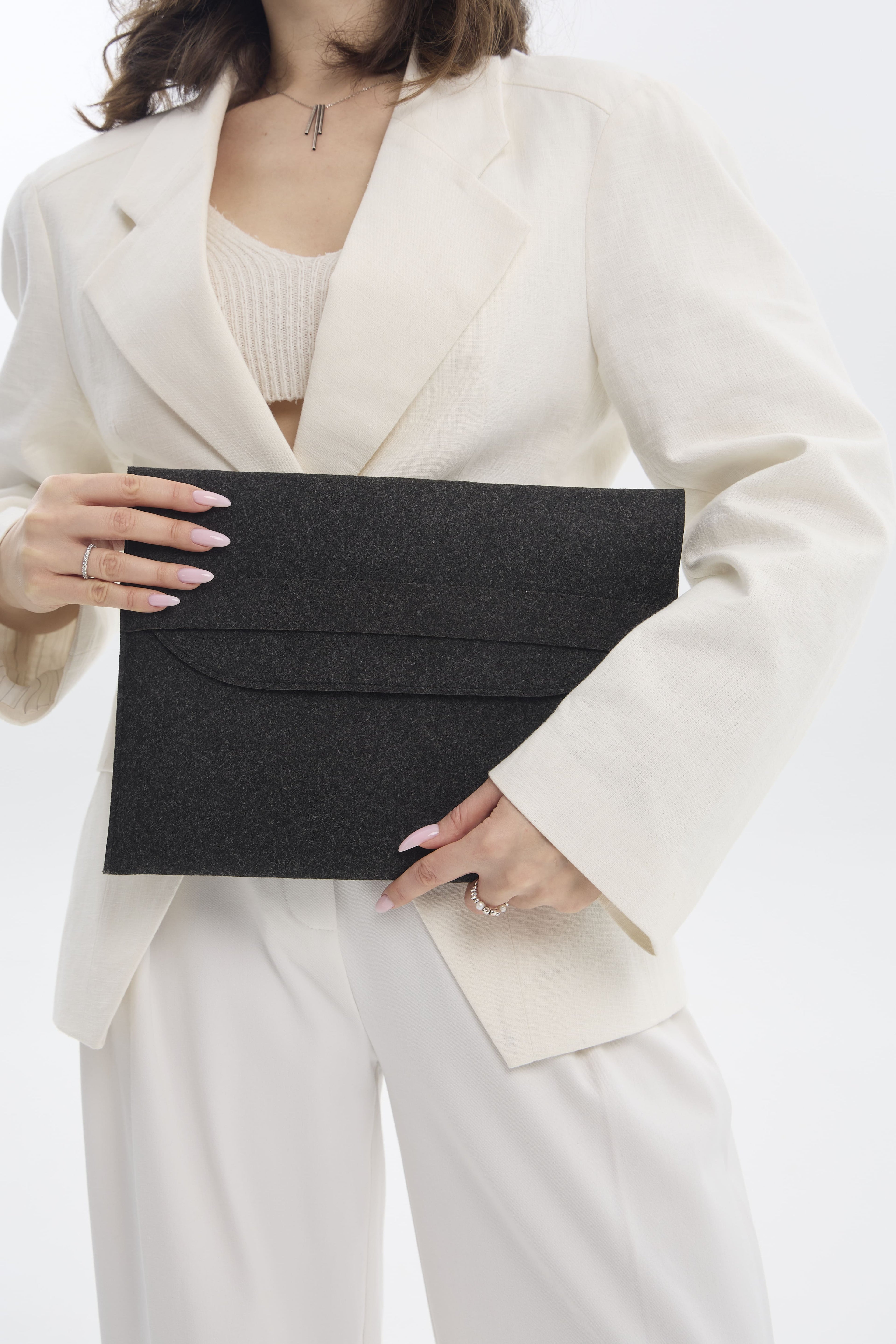 Person holding a black clutch against a white background