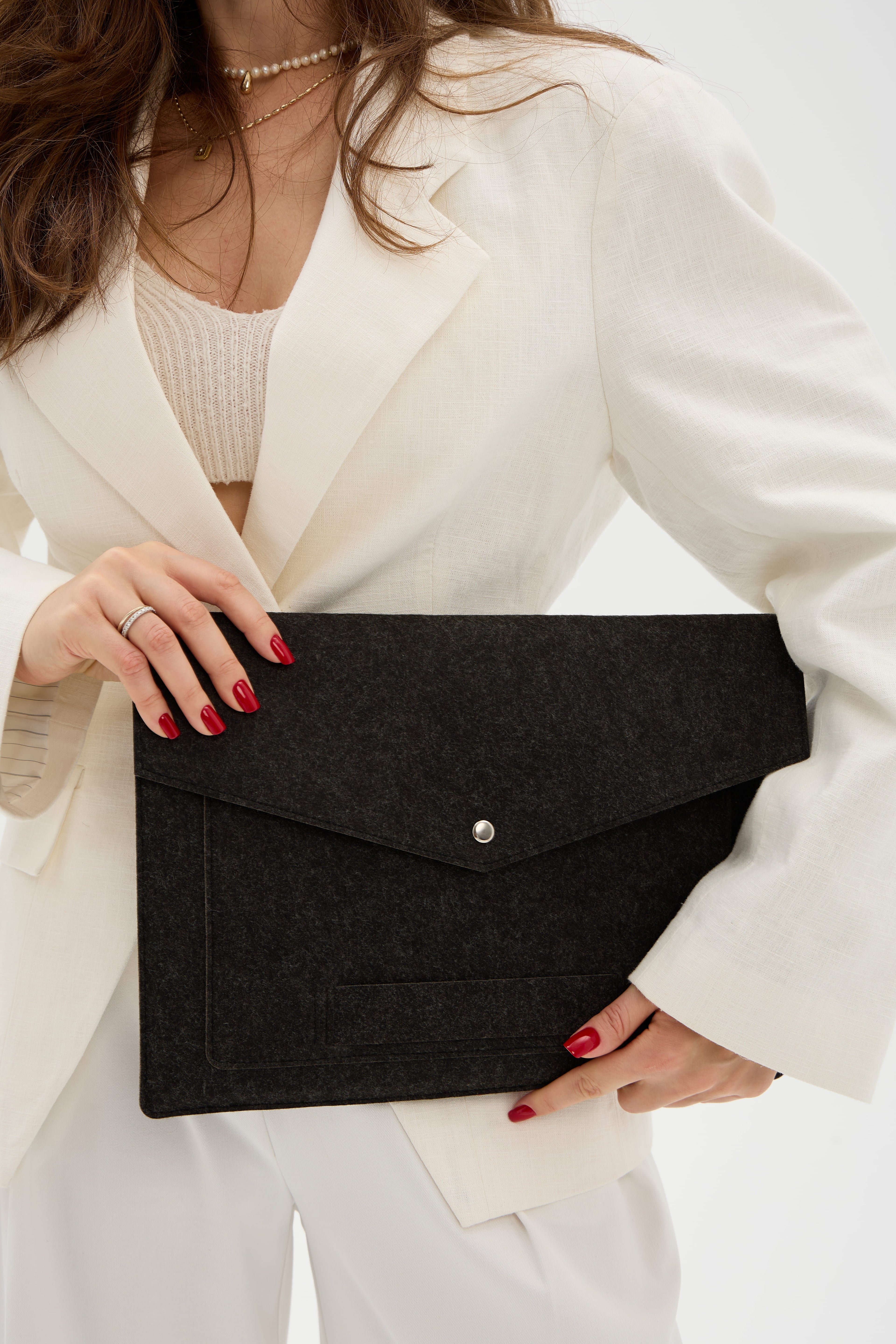 Person holding a black laptop bag against a neutral background