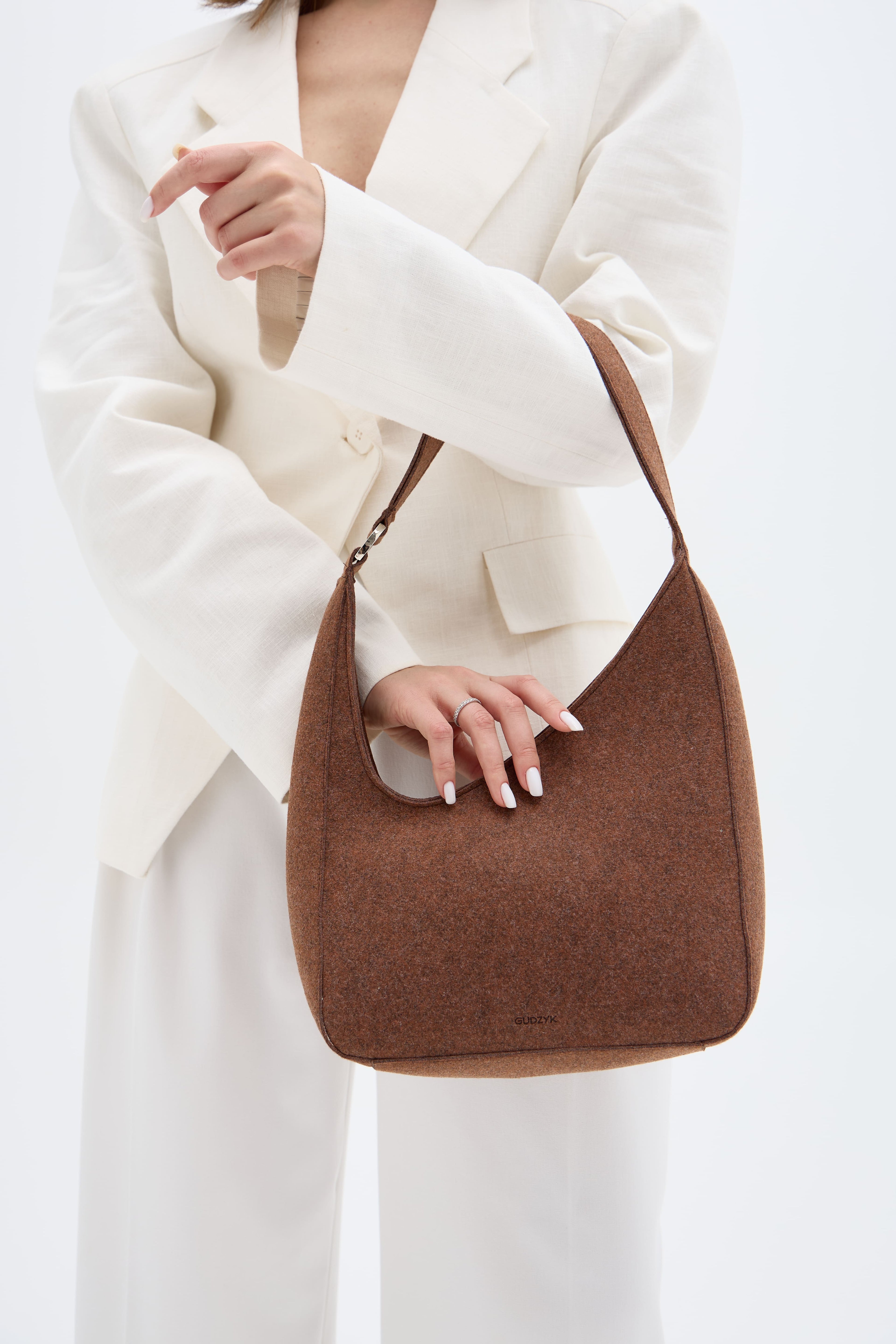 Person holding a brown handbag against a white background