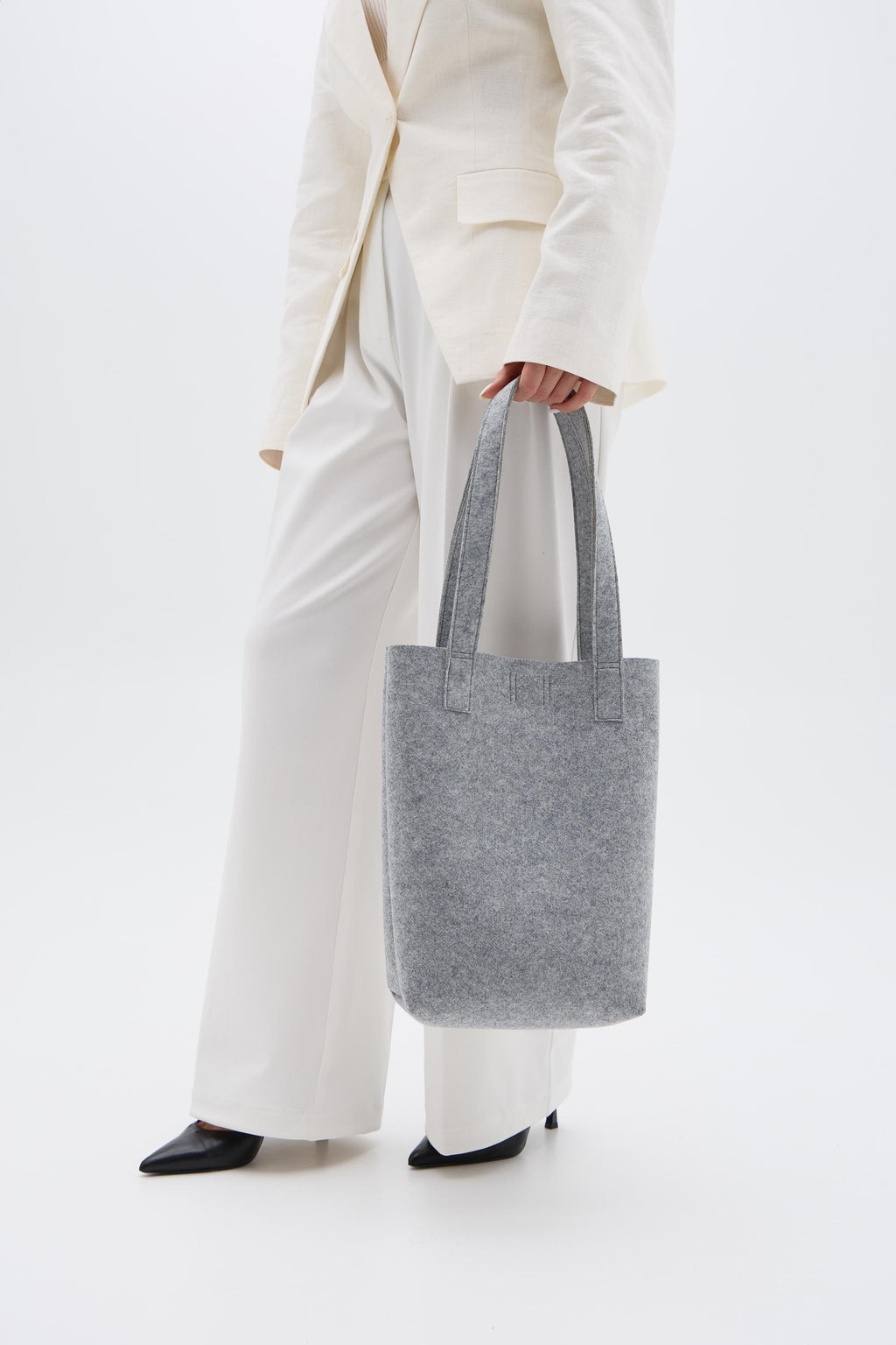 Person holding a silver tote bag against a white background