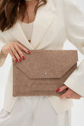 Person holding a beige laptop bag against a neutral background