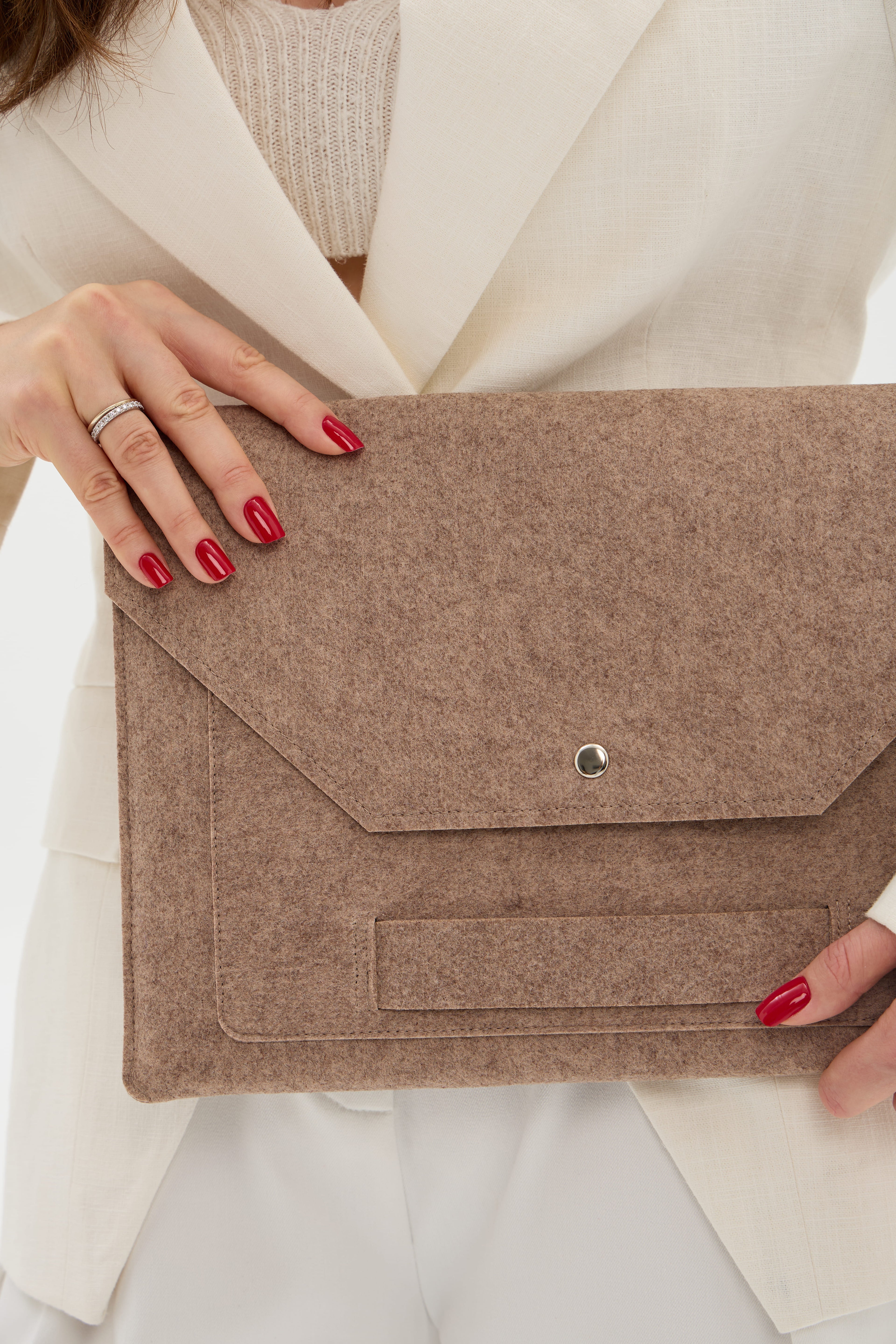 Person holding a beige felt laptop bag with a plain background