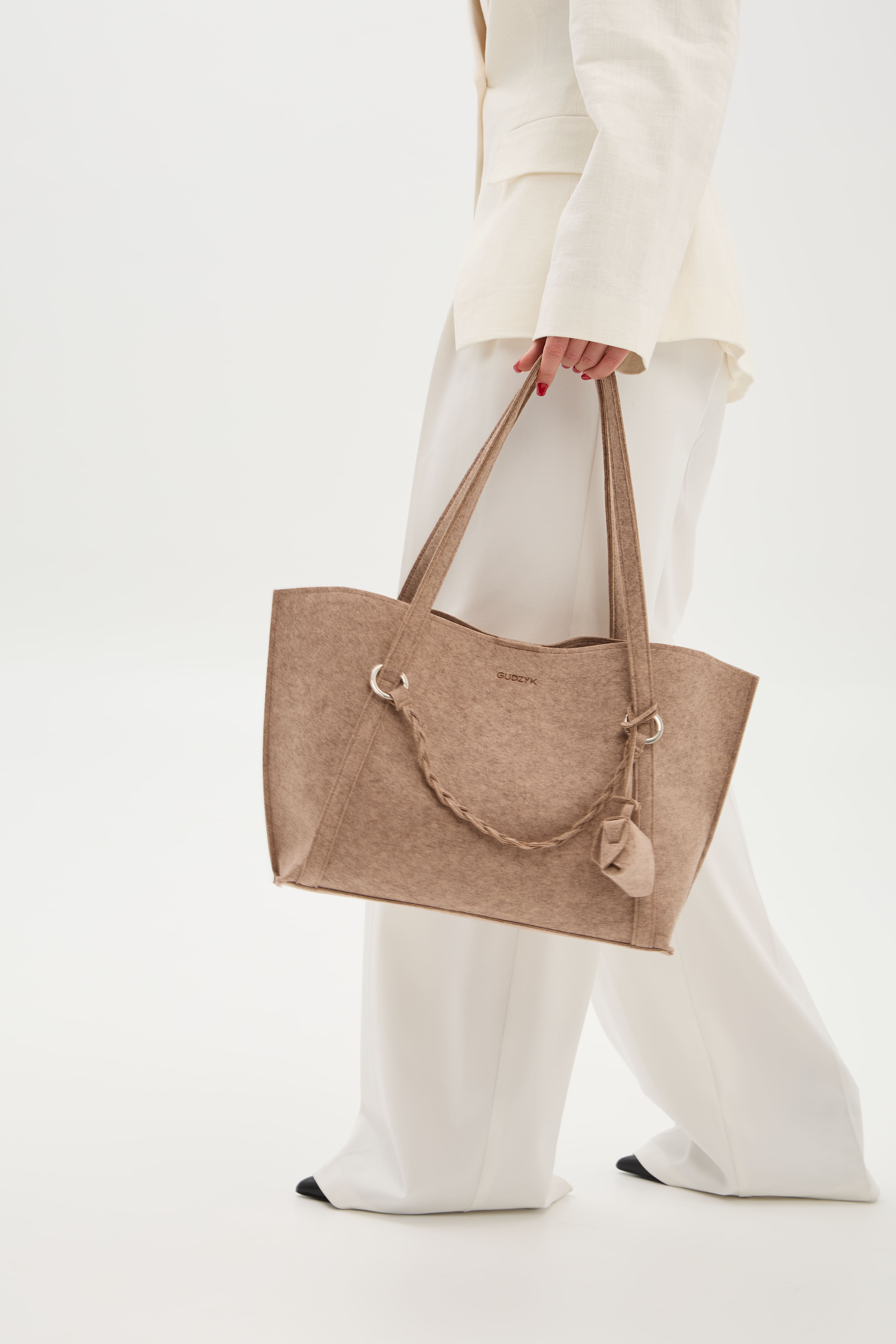 Person holding a beige tote bag on a white background