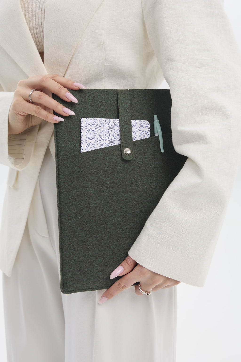 Person holding a dark green case with a pocket against a white background.