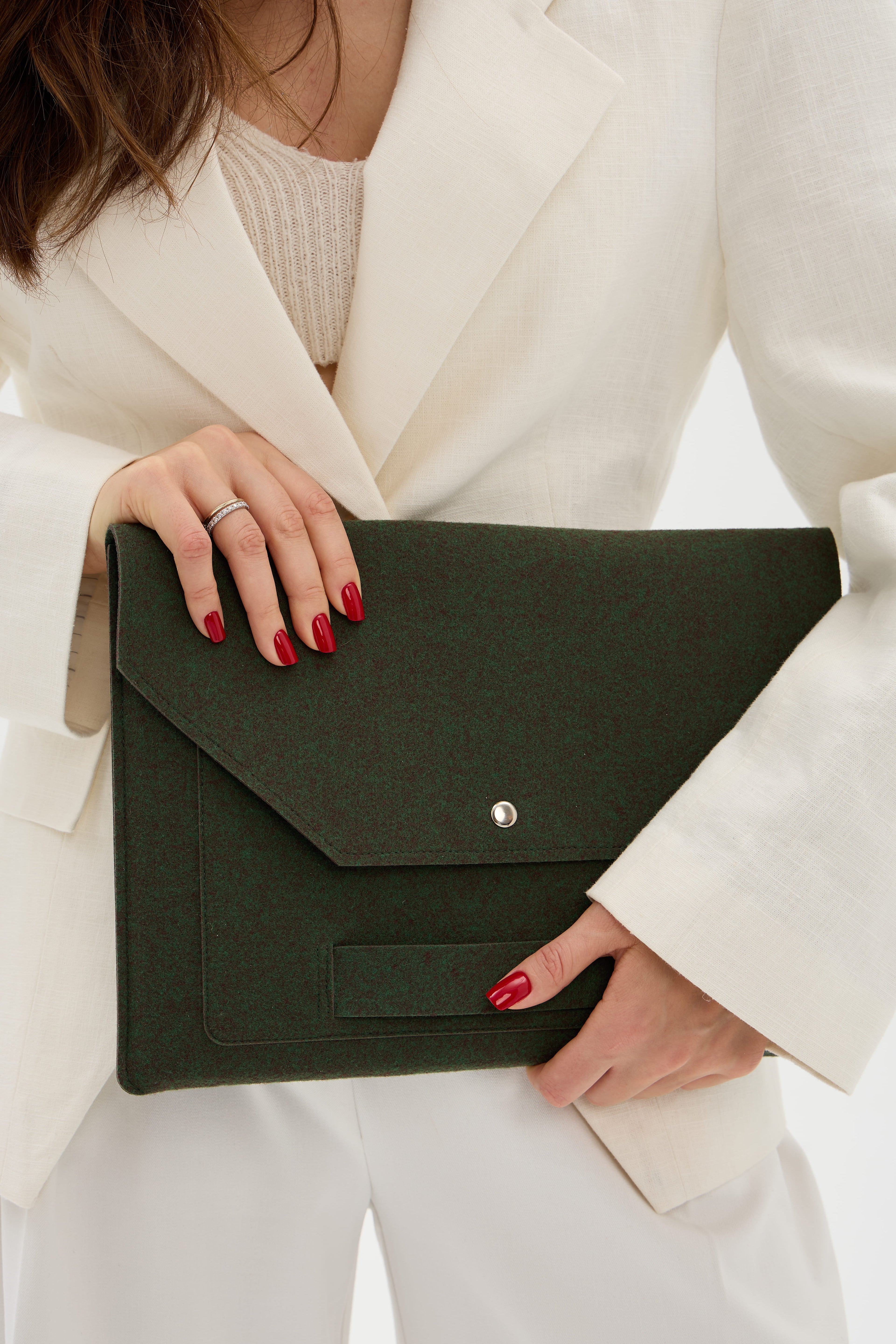 Person holding a dark green laptop bag with a blurred background