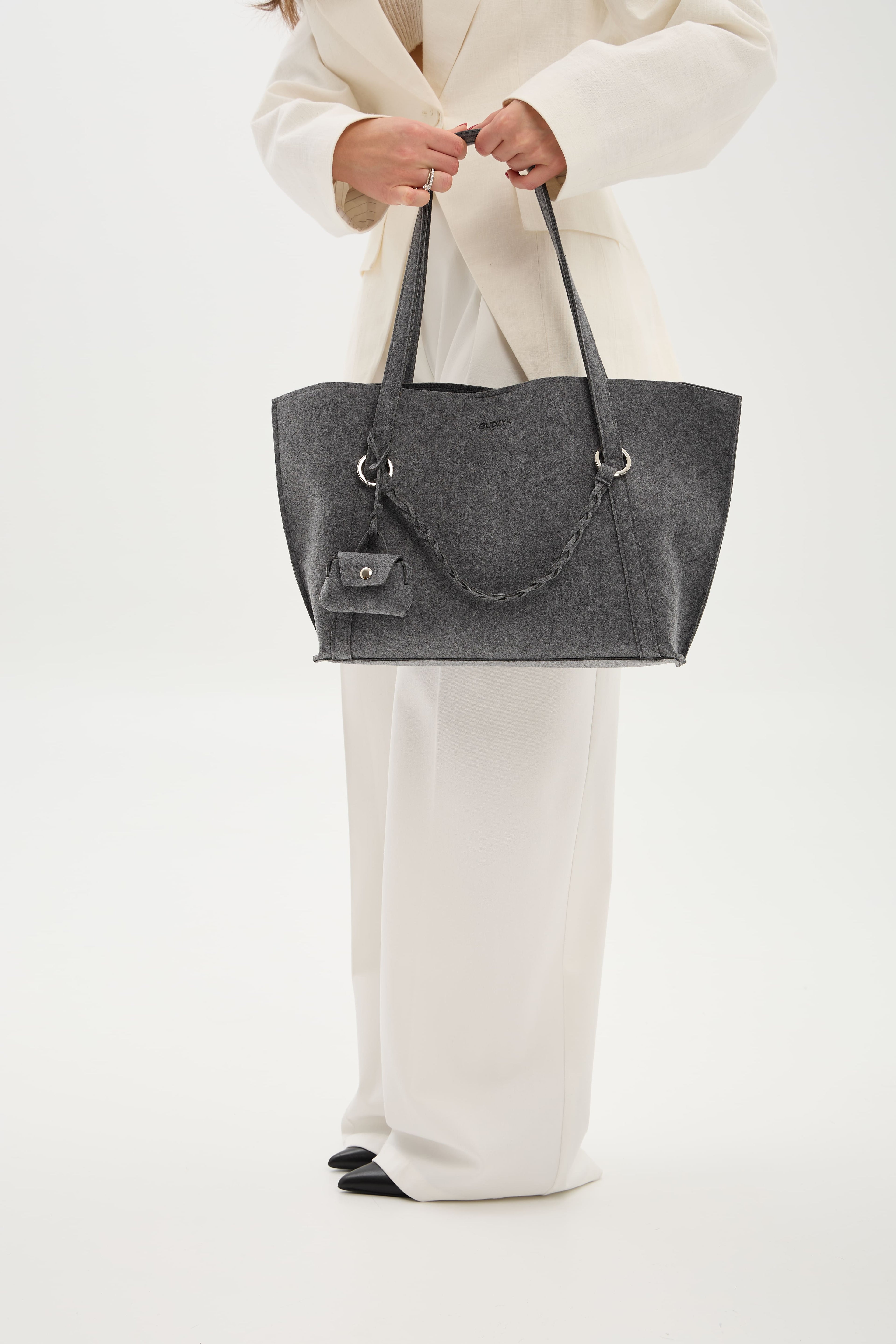 Person holding a gray tote bag against a white background