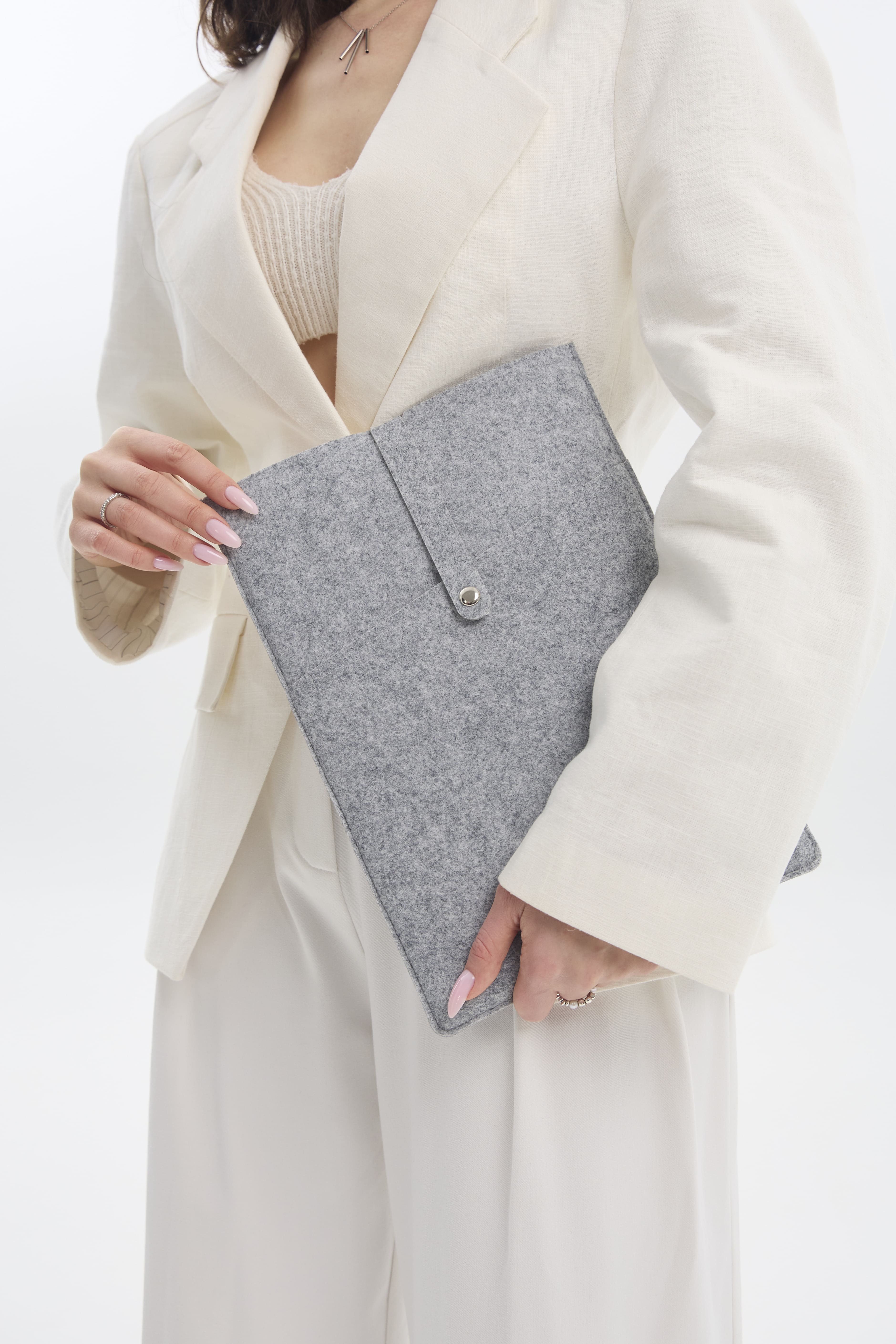 Person holding a silver ecofelt case against a white background