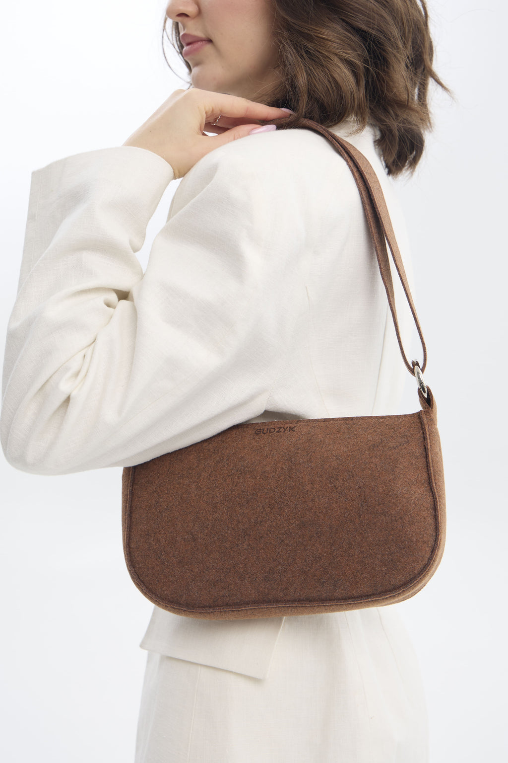 Person wearing a brown crossbody bag on a white background