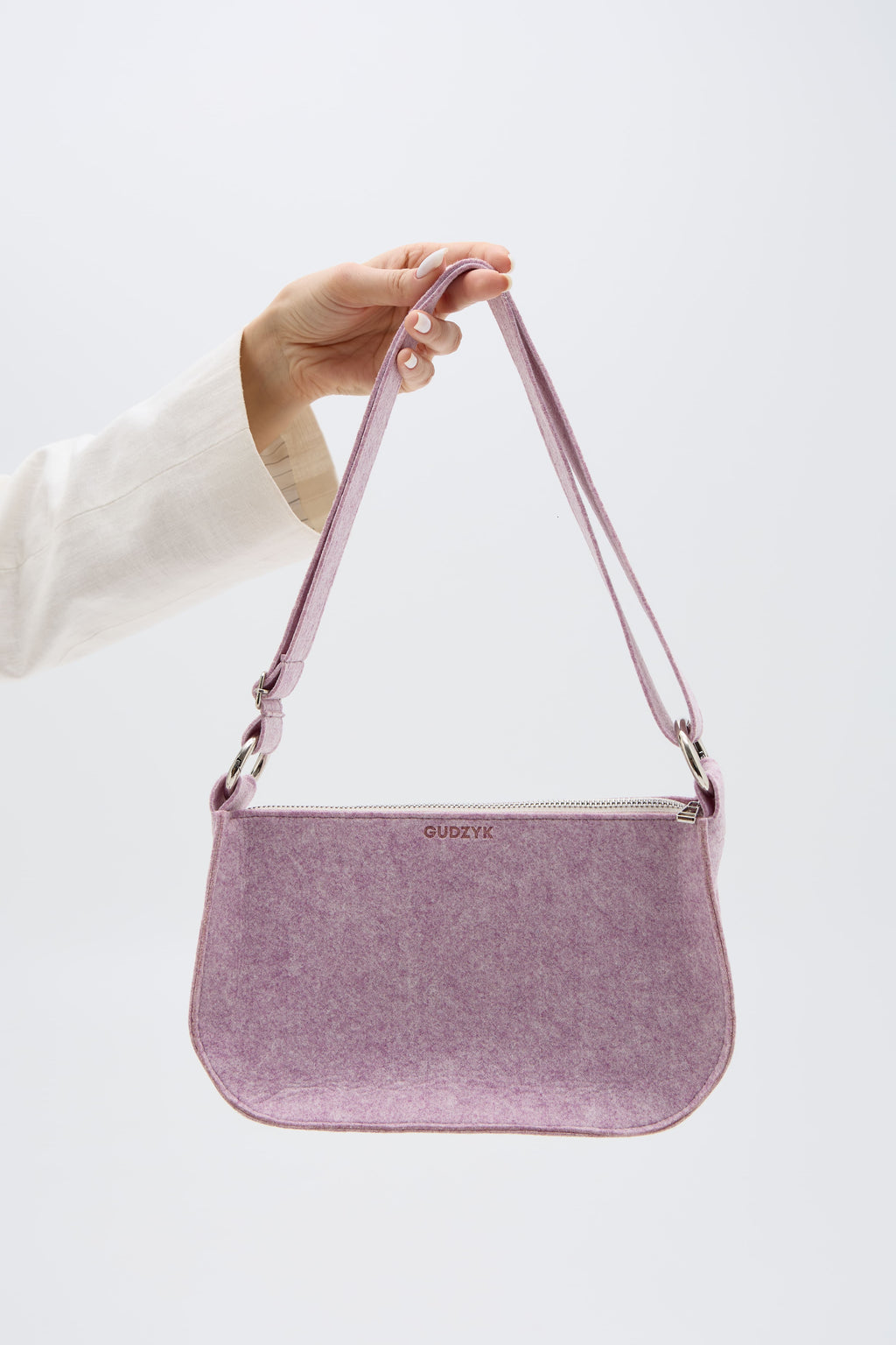 Pink handbag held by a person against a white background