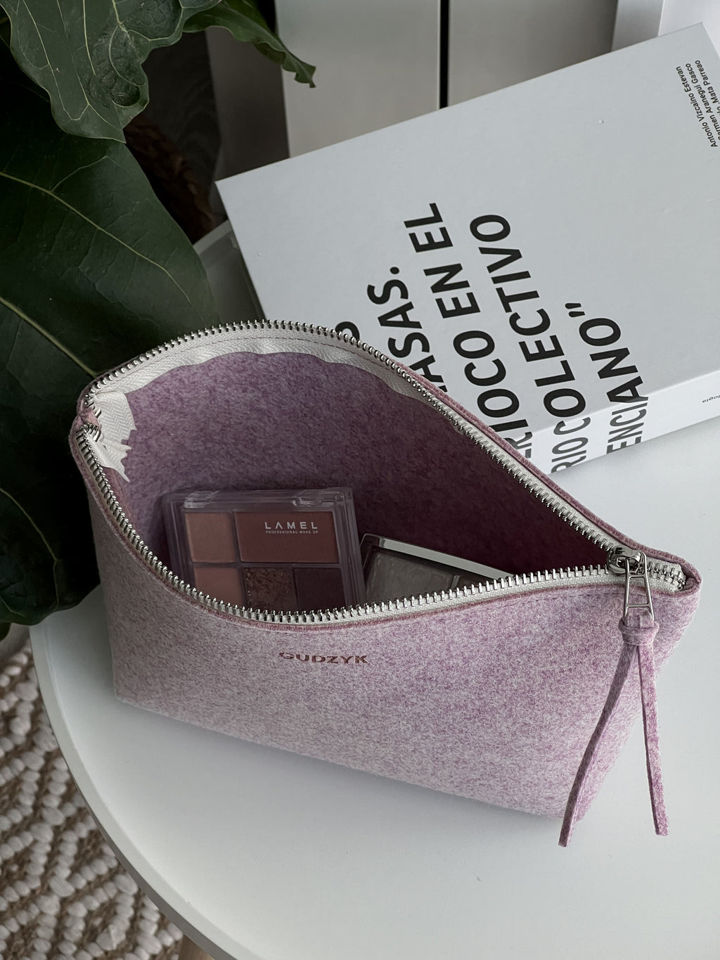 Pink makeup pouch with cosmetic items on a white surface