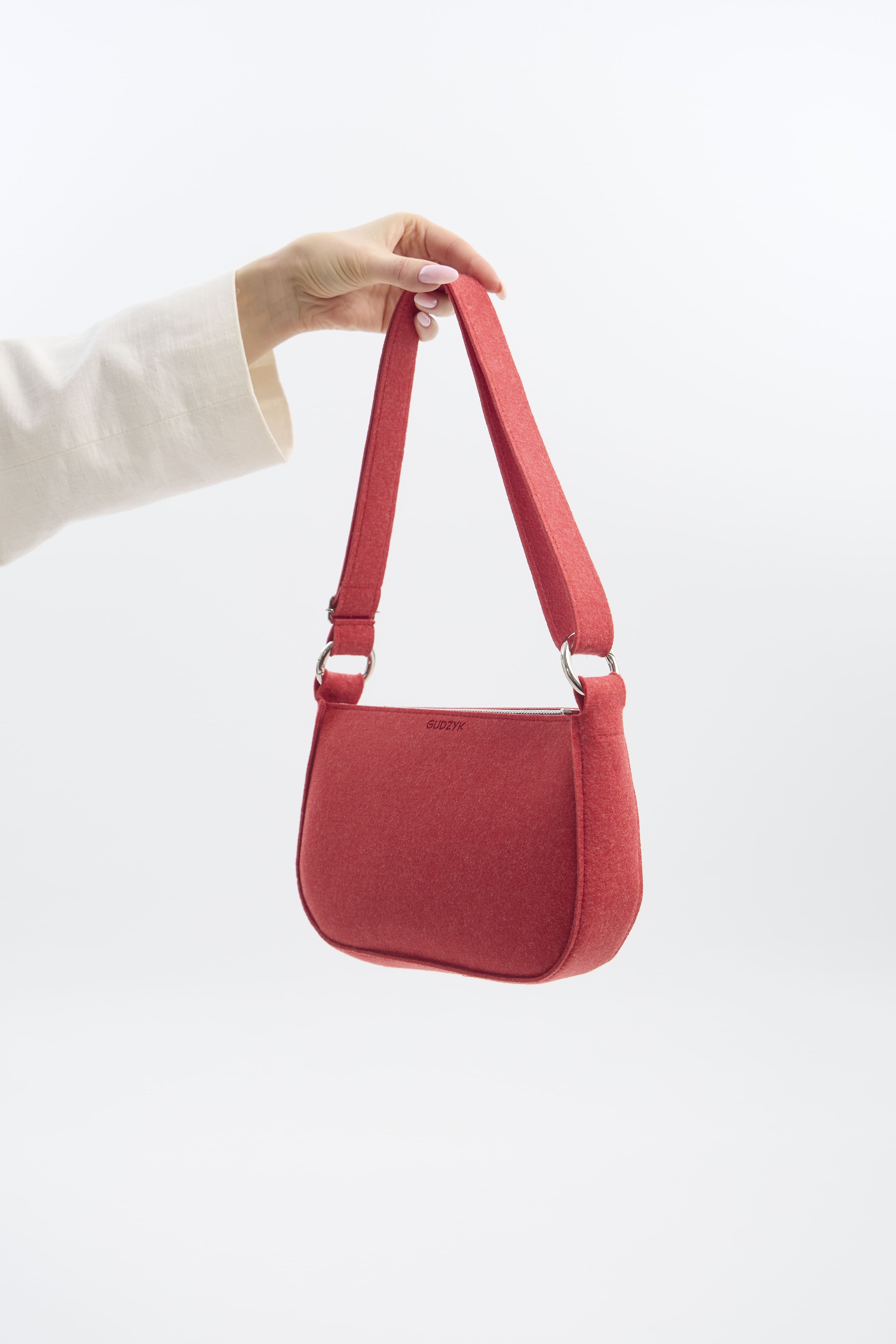 Red handbag held by a person against a white background