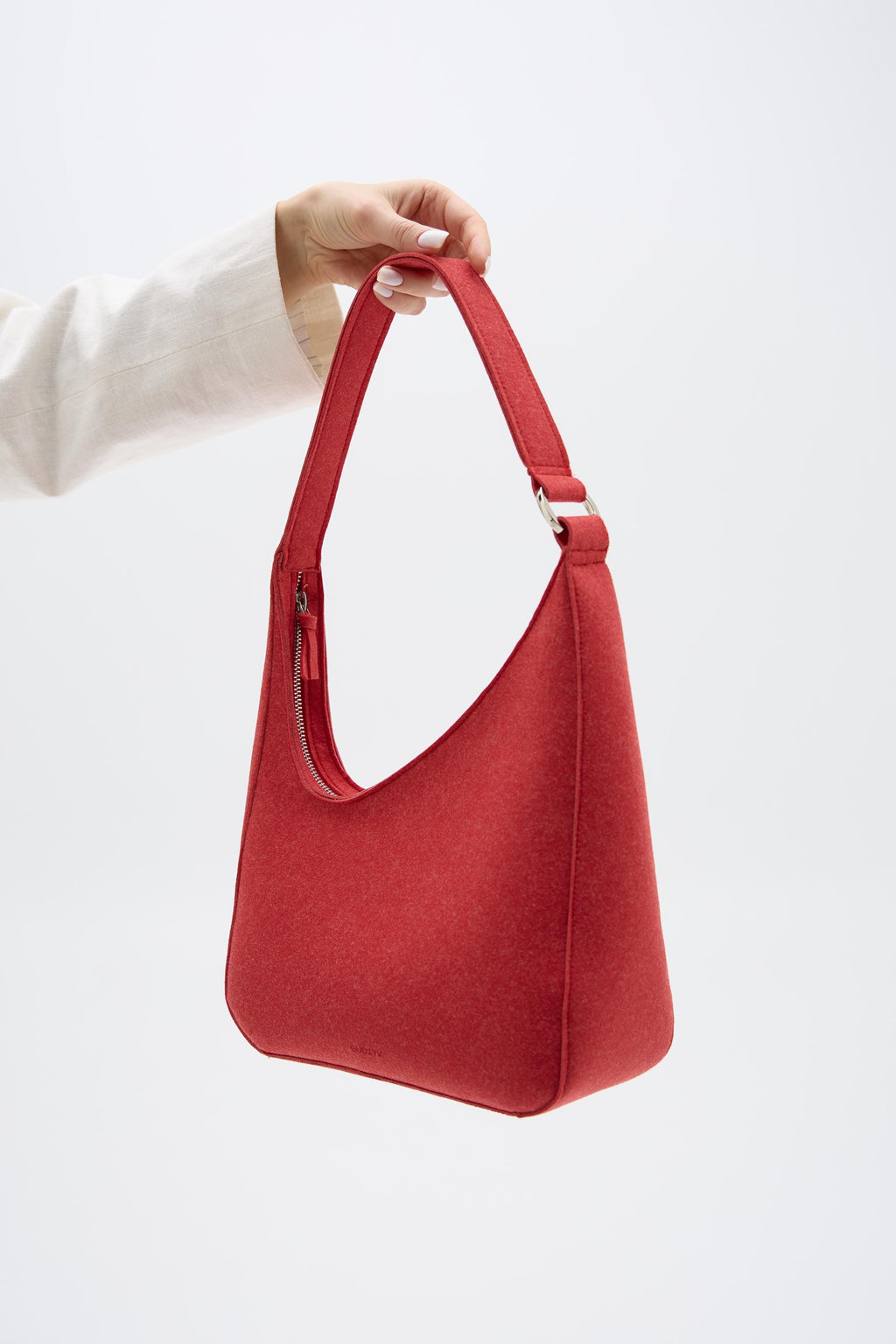 Red handbag held by a person against a white background