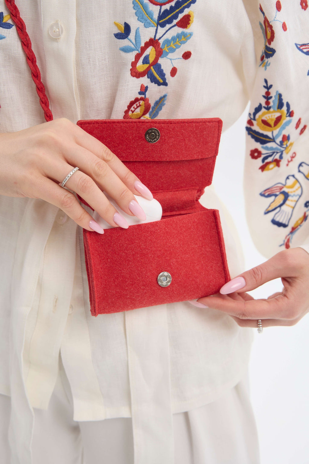 Red felt handbag by a person with a white embroidered background