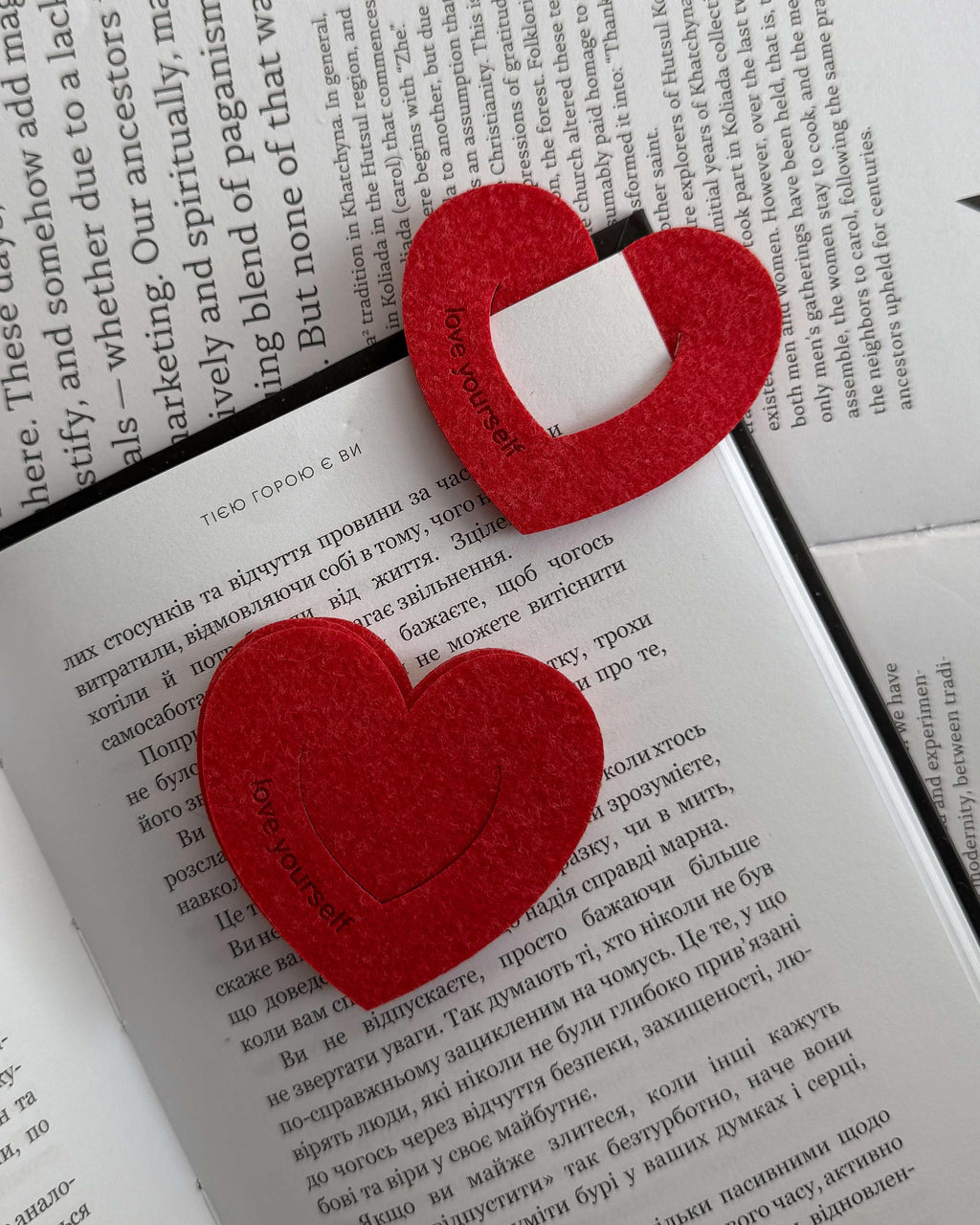 Red heart-shaped bookmarks on an open book with text.