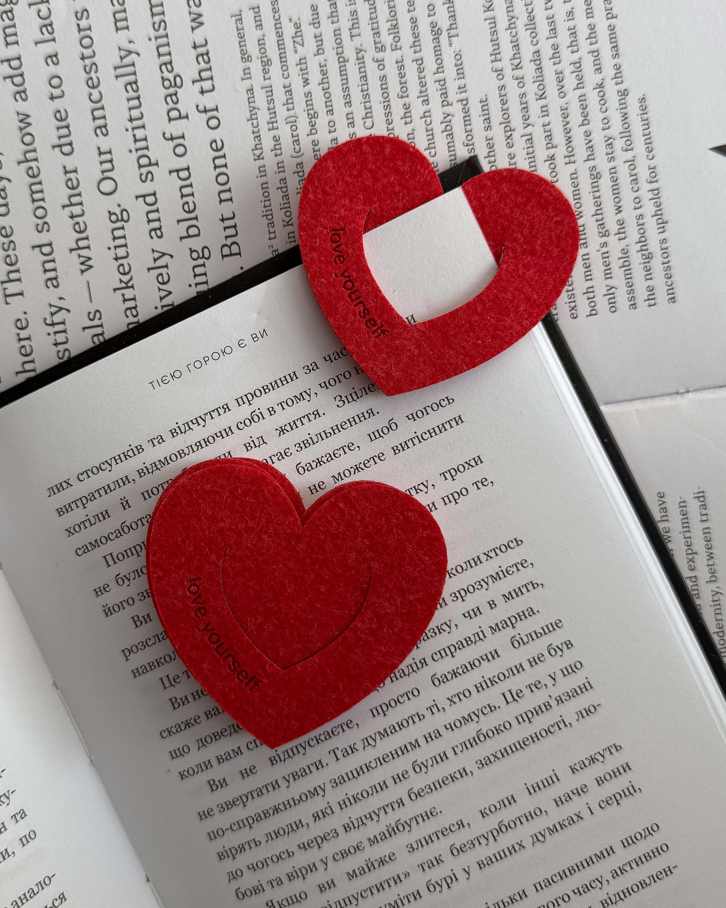 Red heart-shaped bookmarks on an open book with text.