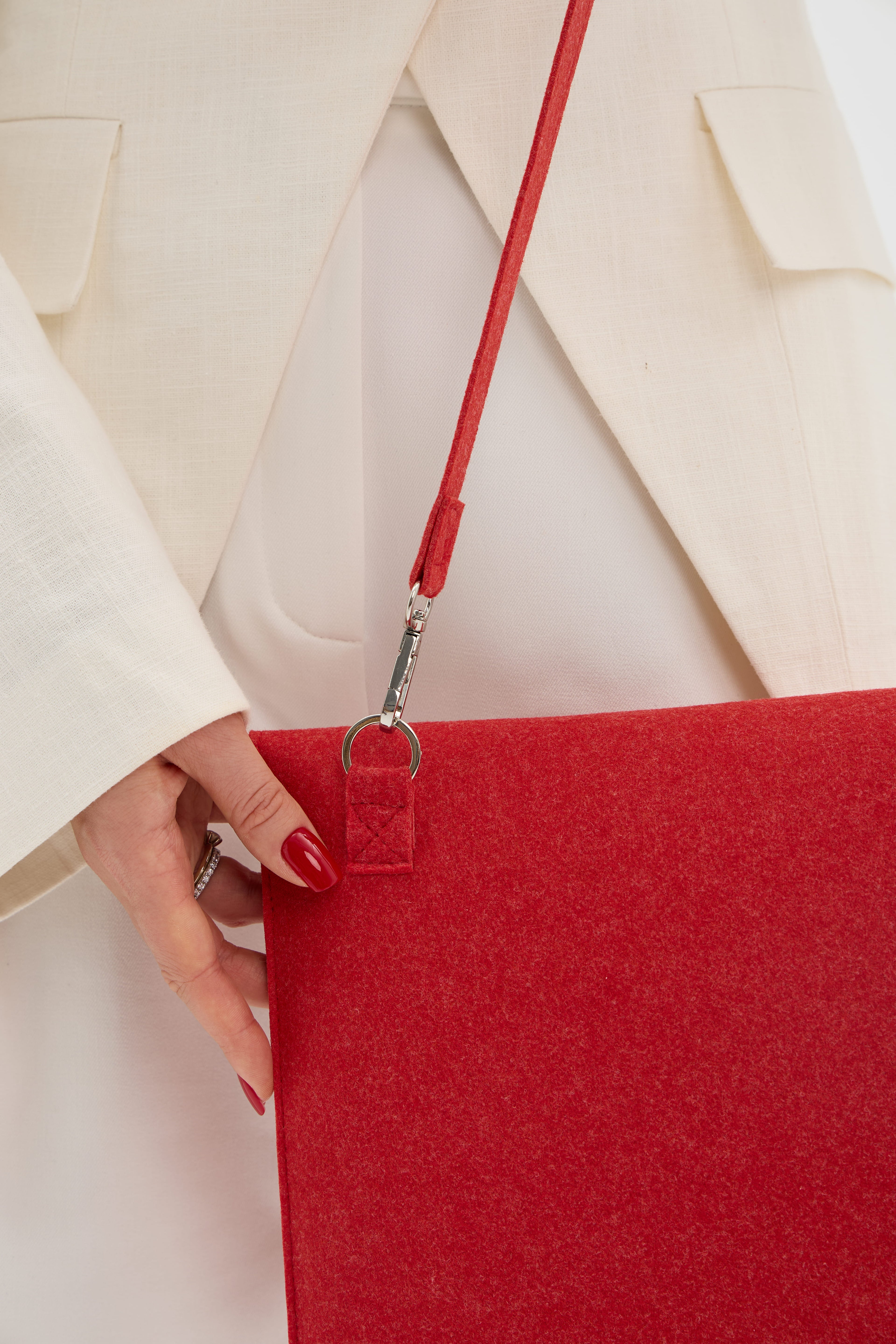 Red laptop bag with a strap held by a hand against a white background