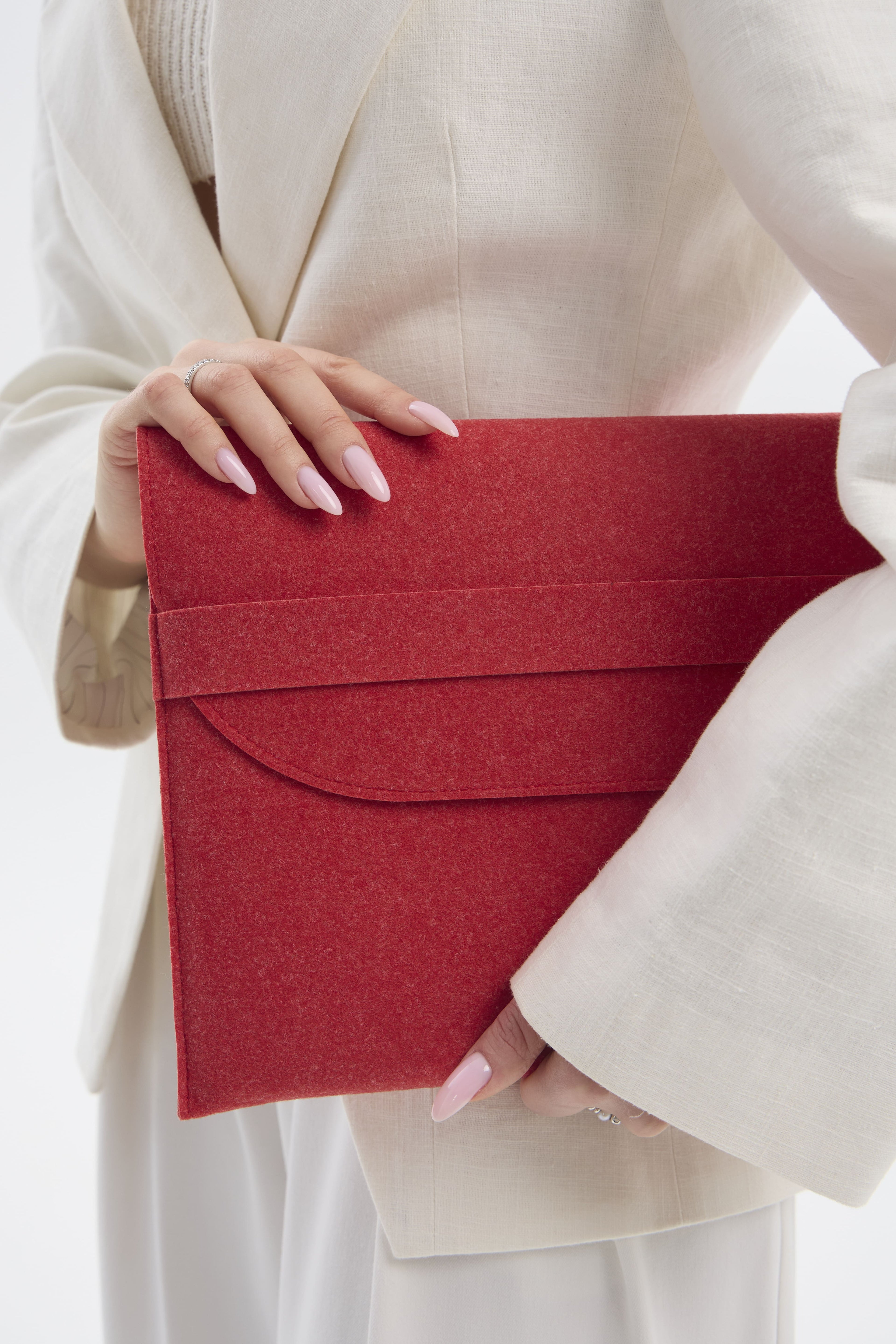 Red sleeve held by a person wearing a beige outfit on a white background