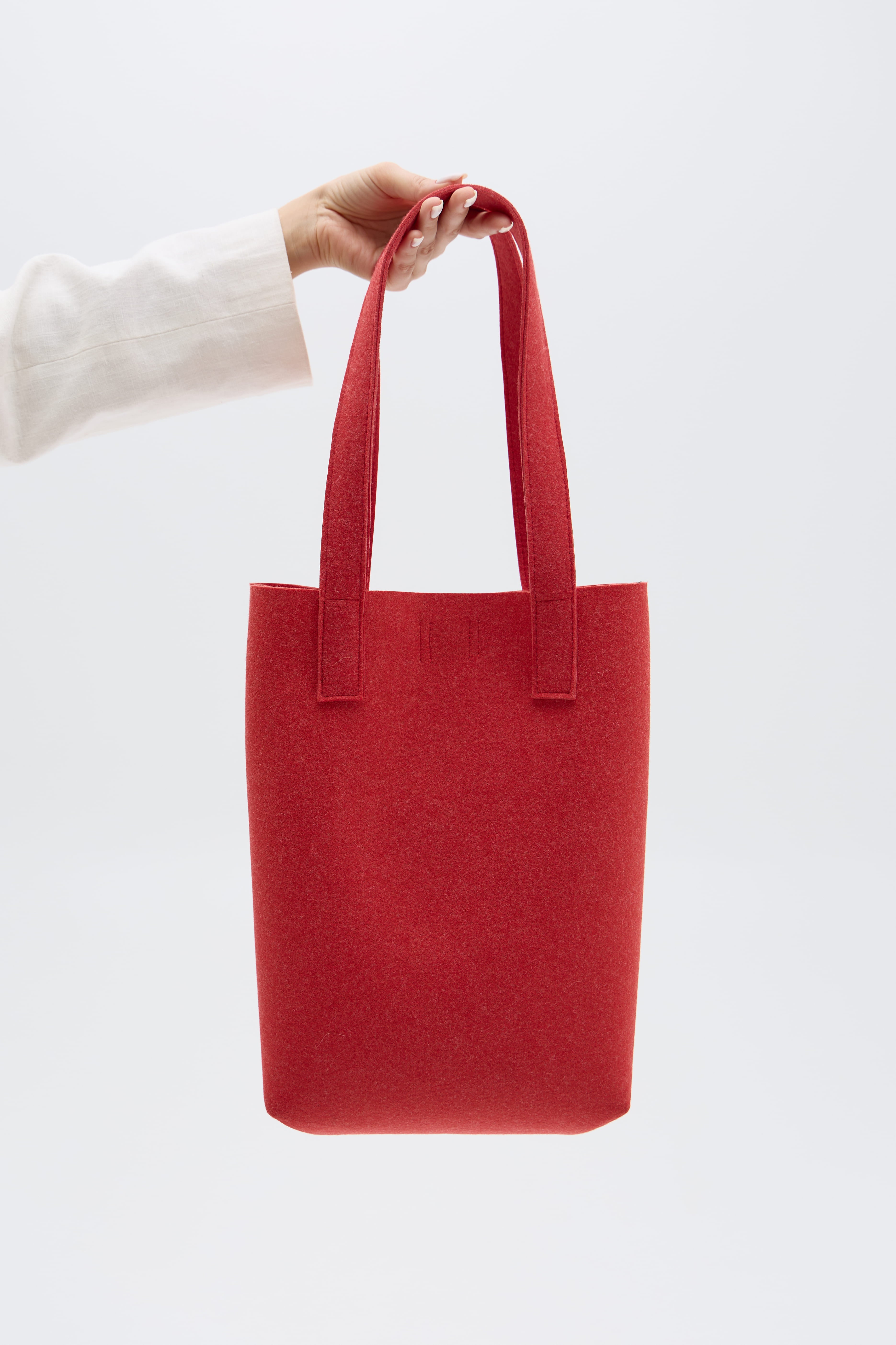 Red tote bag held by a person against a white background