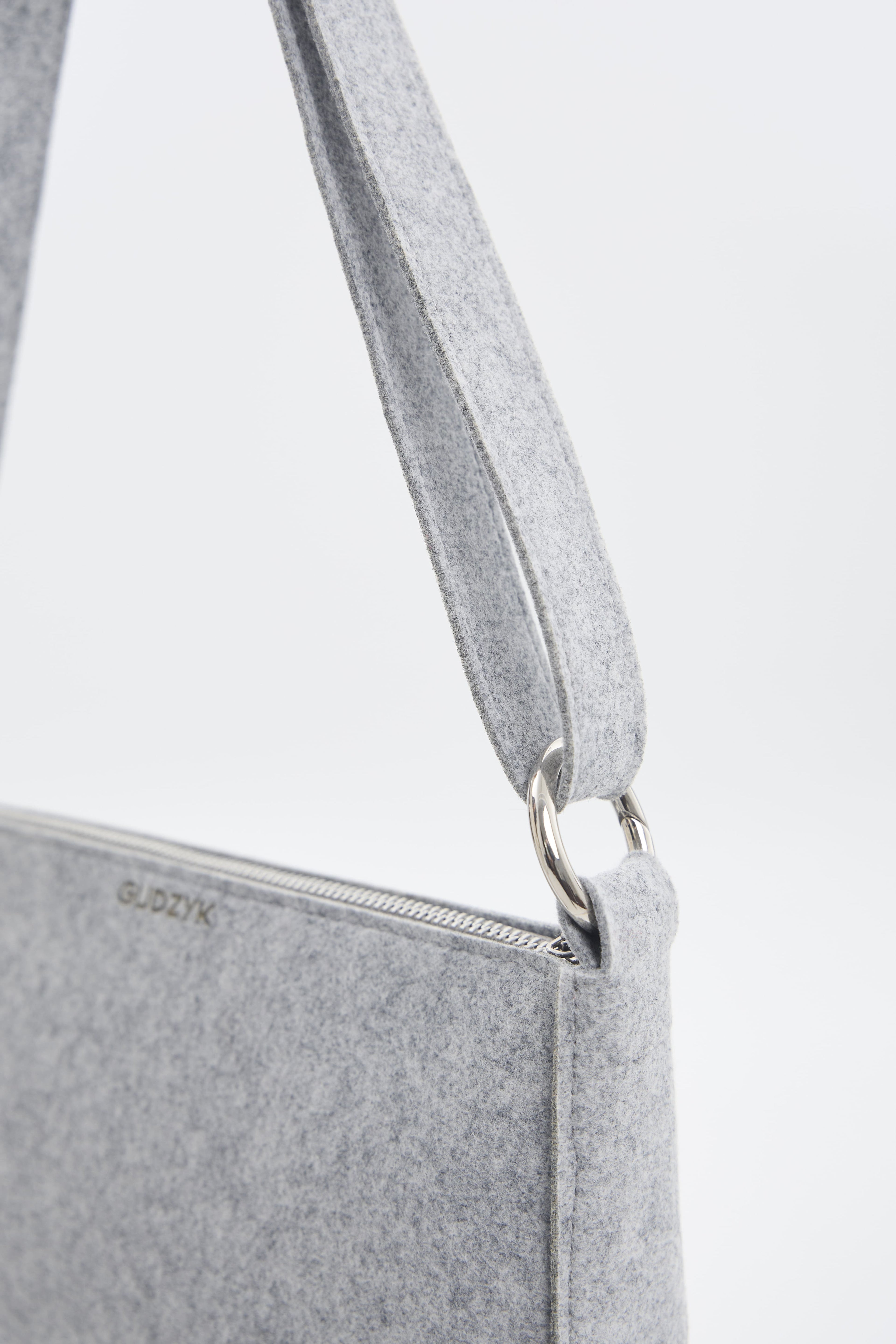 Gray crossbody bag with a visible brand logo on a light gray background