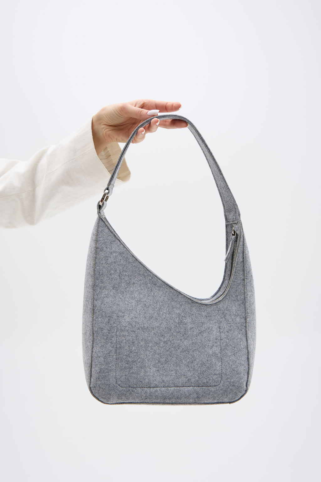 Silver shoulder bag held by a person against a white background