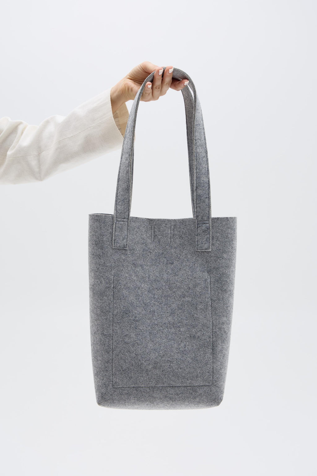 Silver tote bag held by a person against a white background