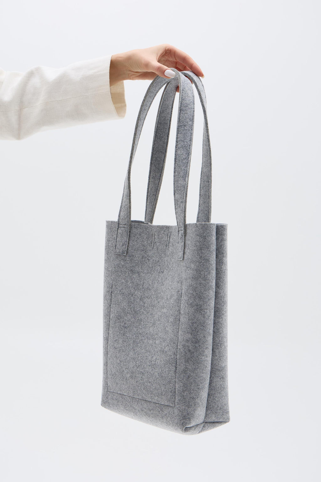 Silver tote bag held by a person against a white background