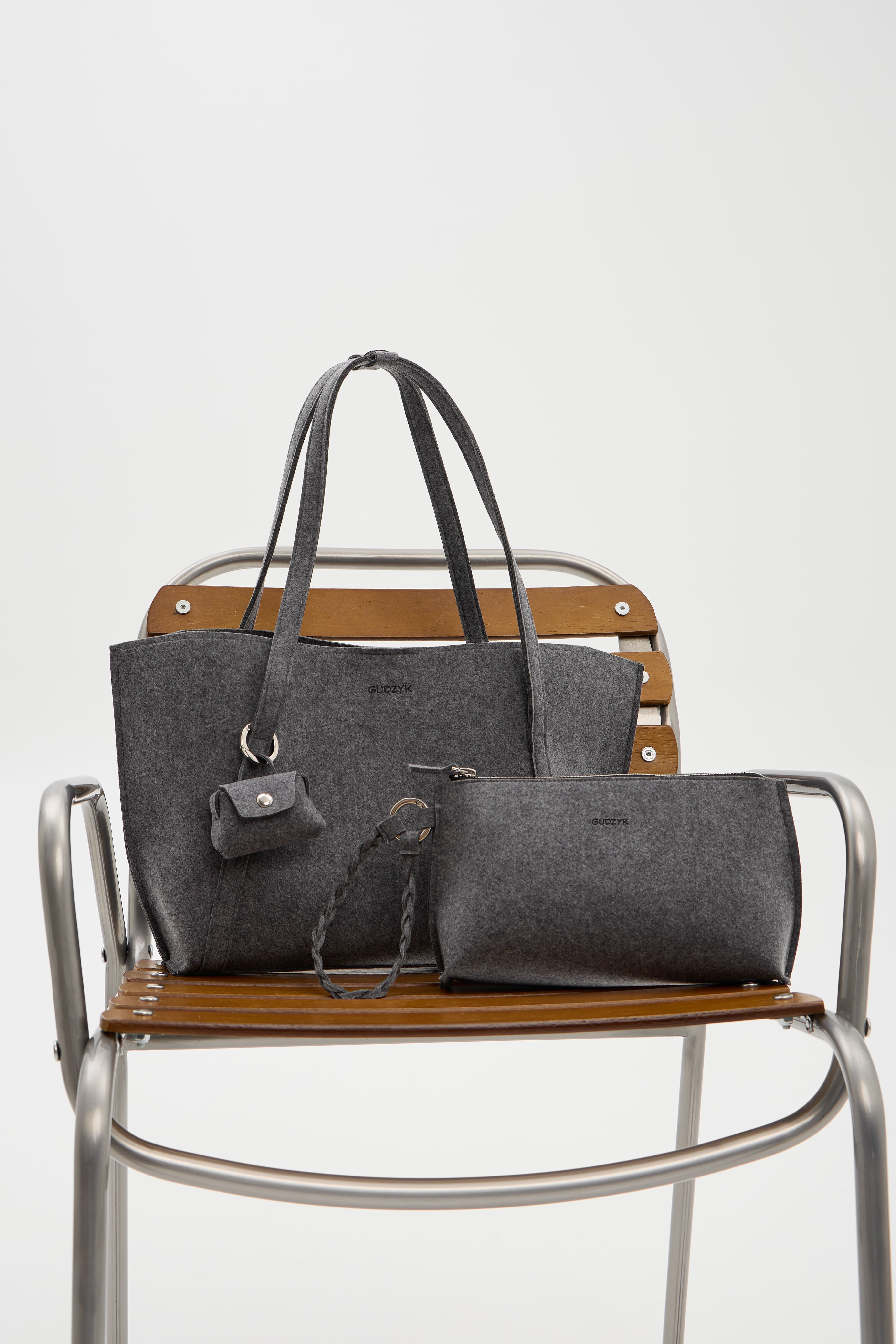 Two gray handbags on a wooden chair with a white background