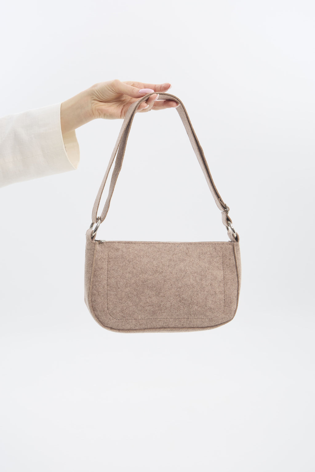 Beige handbag held by a person against a white background
