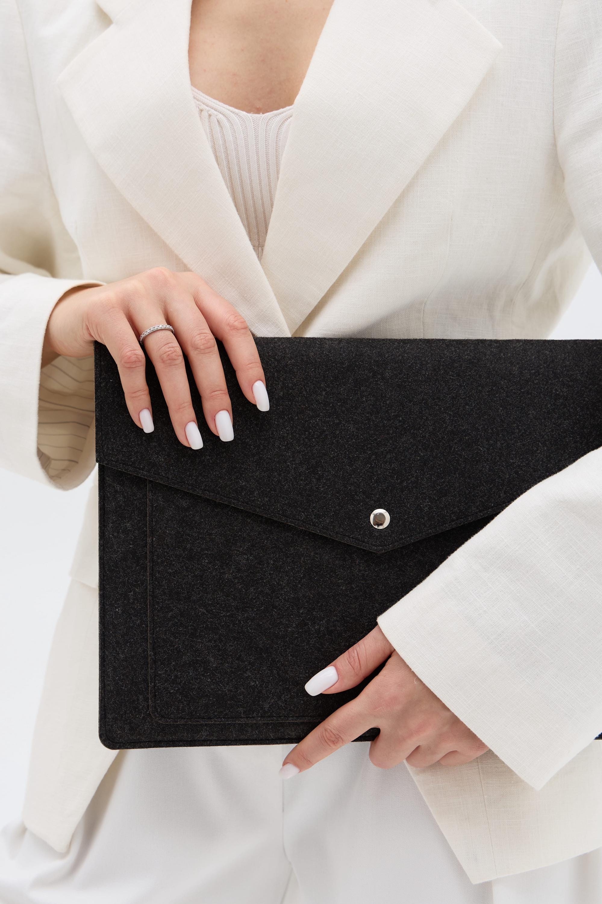 Person holding a black laptop case against a white background