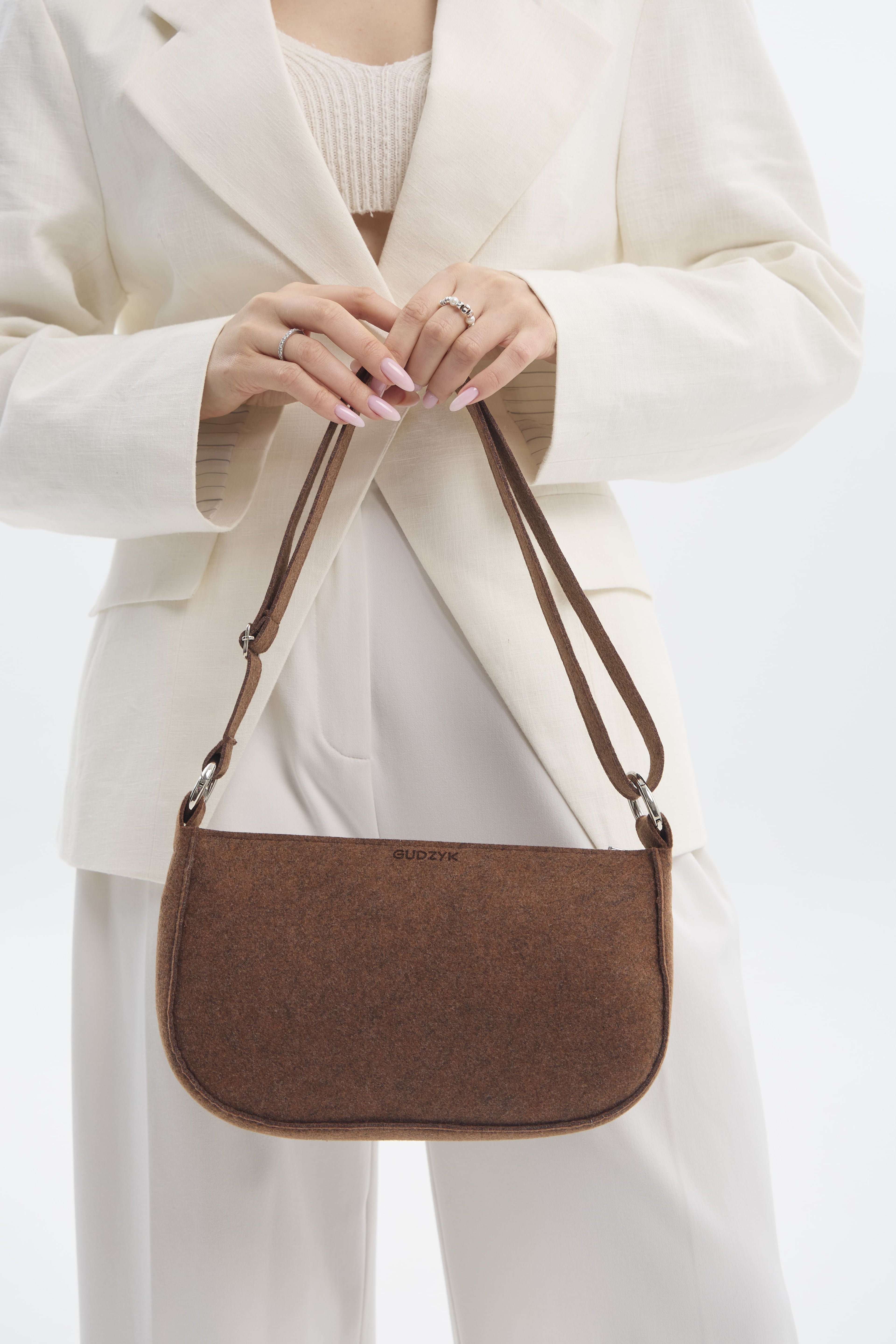 Person holding a brown handbag against a white background