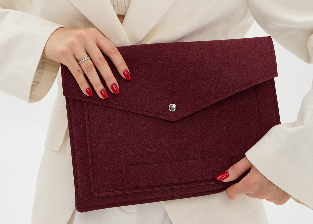 Woman holding a burgundy laptop case against a white background