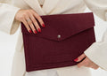 Woman holding a burgundy laptop case against a white background