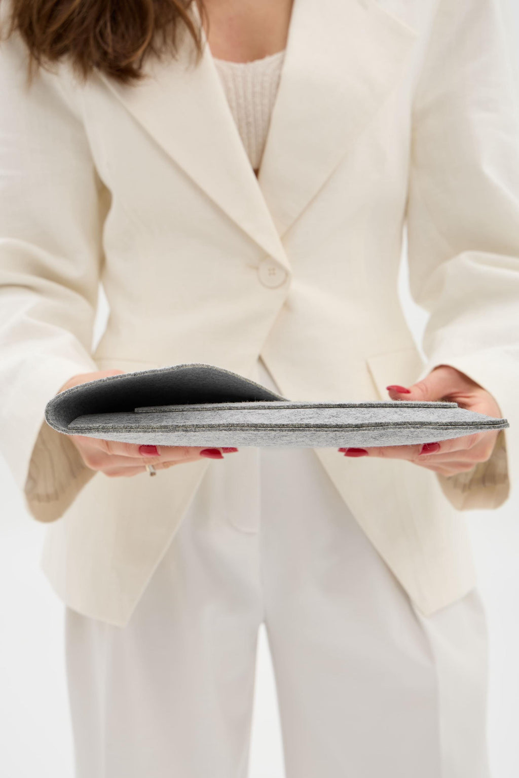 Person wearing a white blazer holding a gray case.