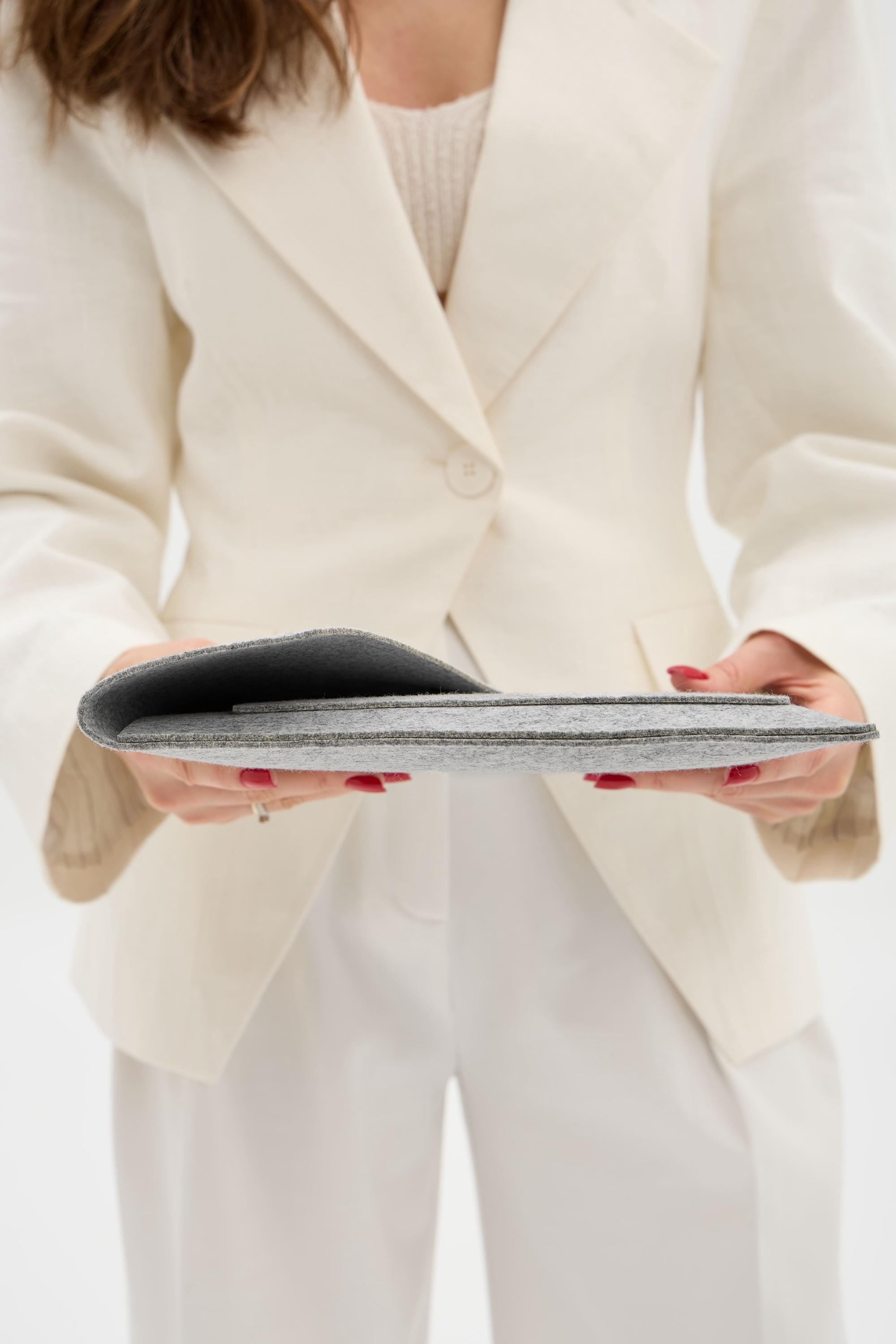 Person wearing a white blazer holding a gray case.