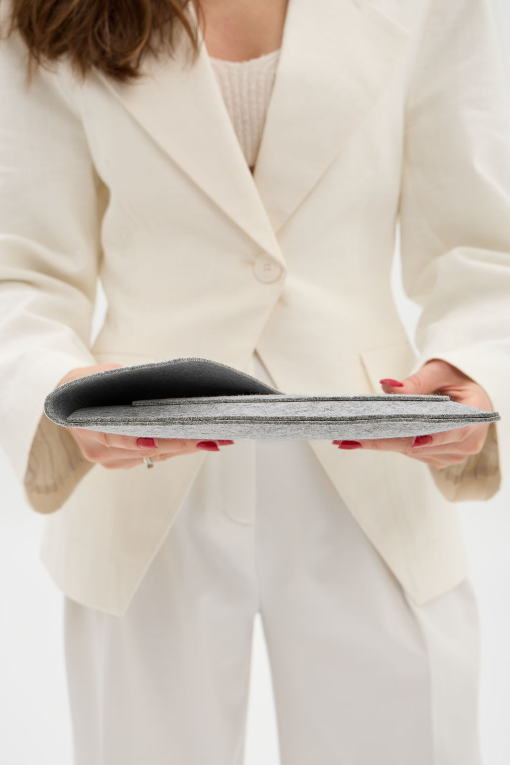 Person wearing a white blazer and pants holding a silver case.