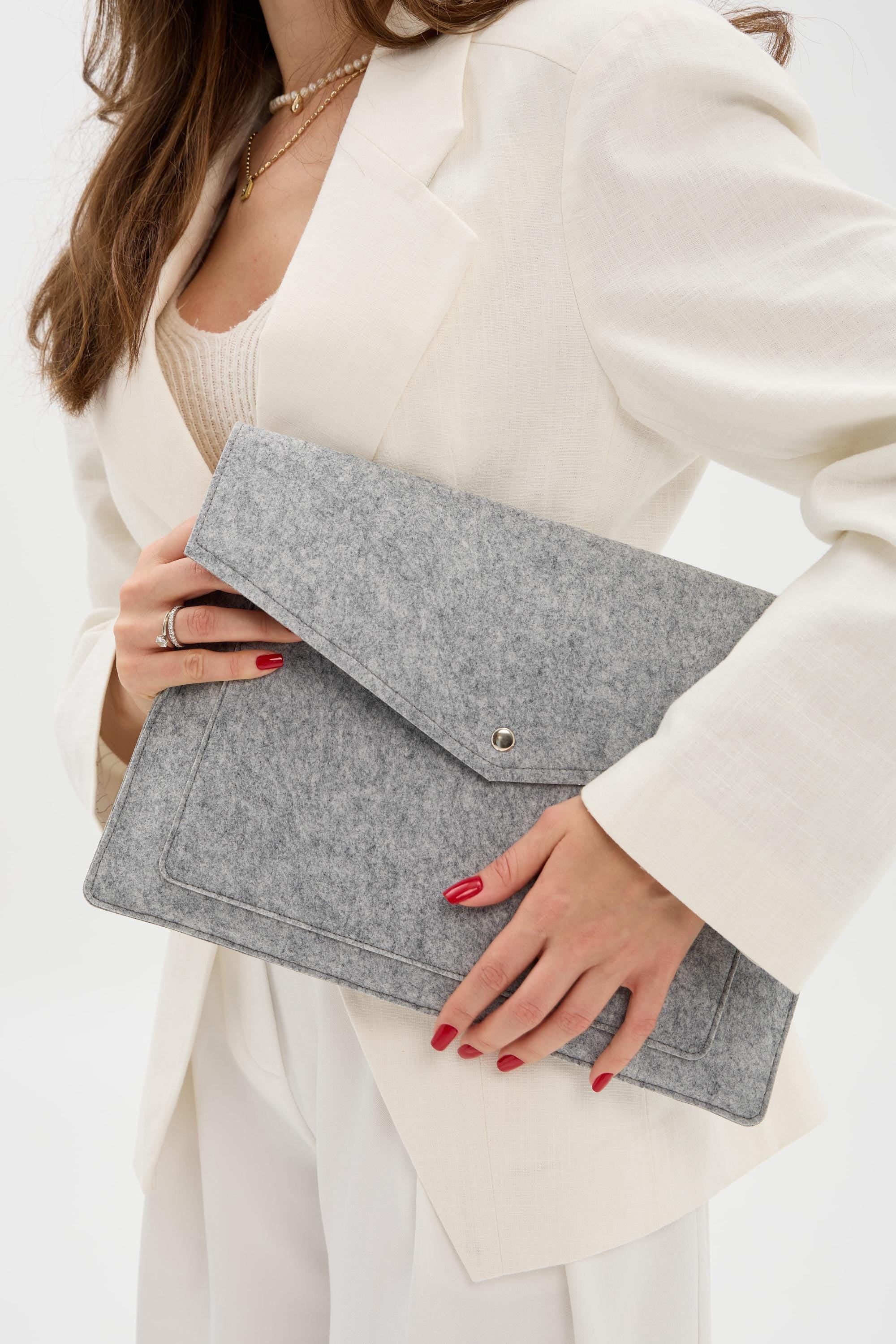 Person holding a silver laptop case against a white background