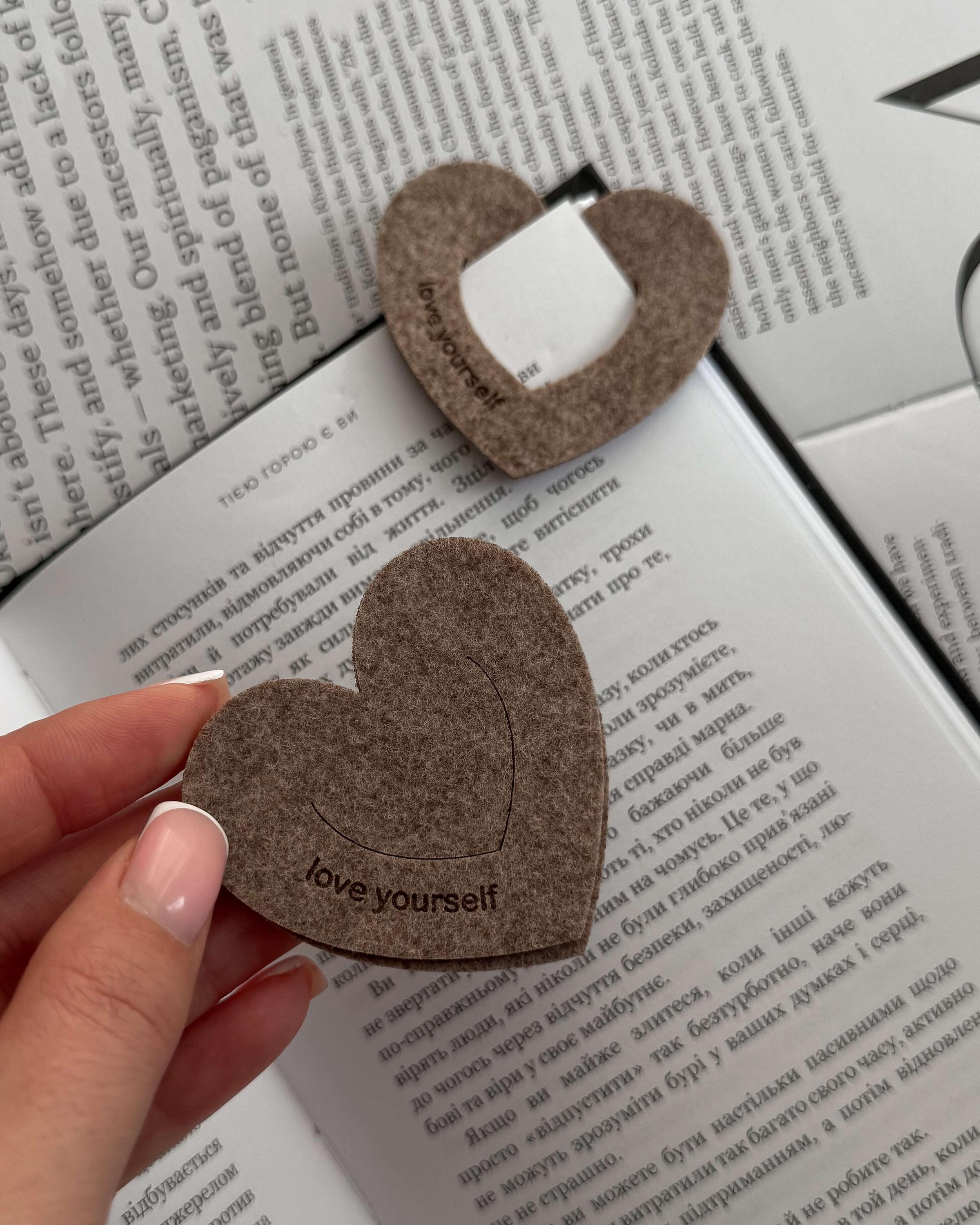 Heart-shaped felt bookmark with 'love yourself' text on an open book