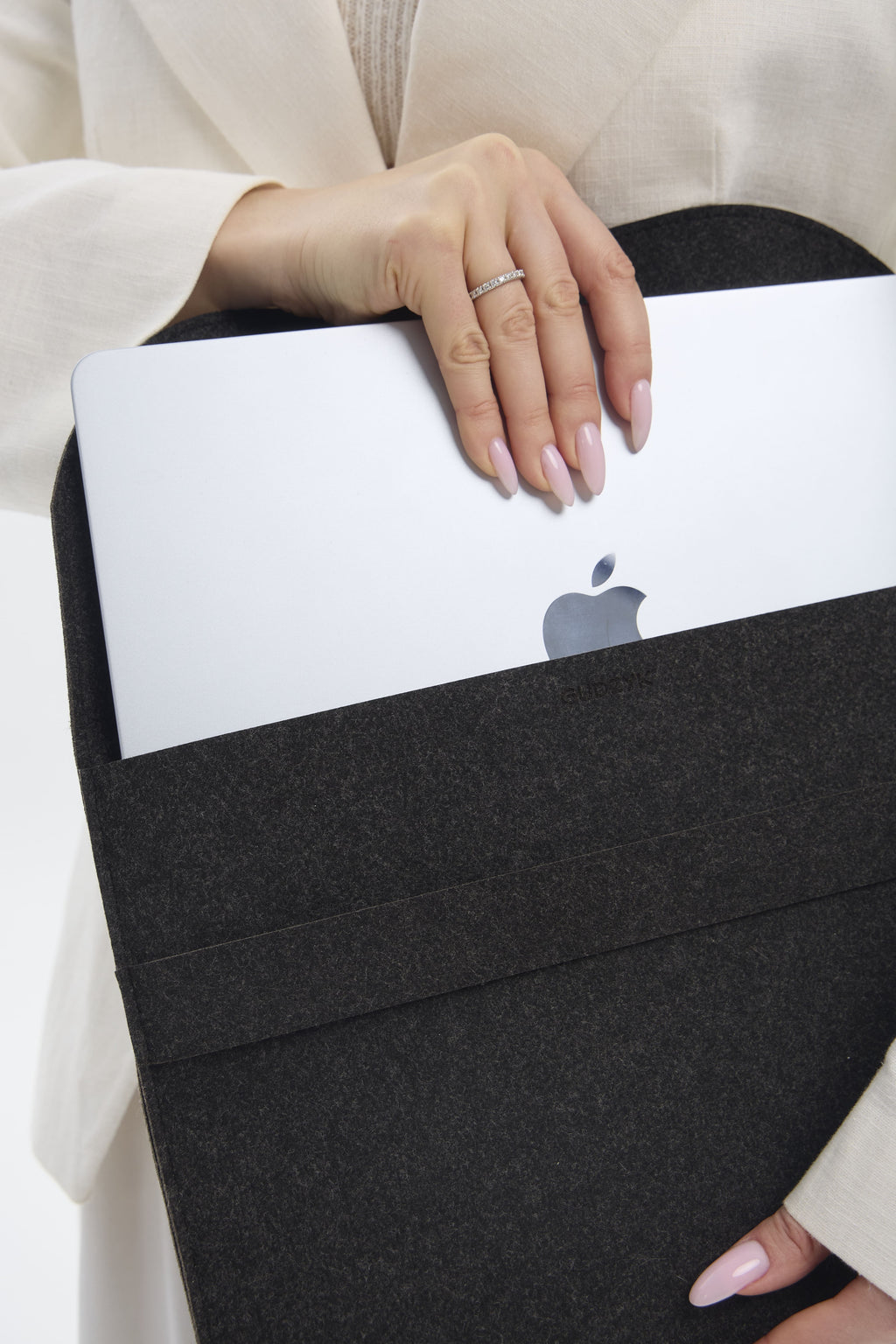 Person holding a black laptop sleeve with an Apple logo on a white background