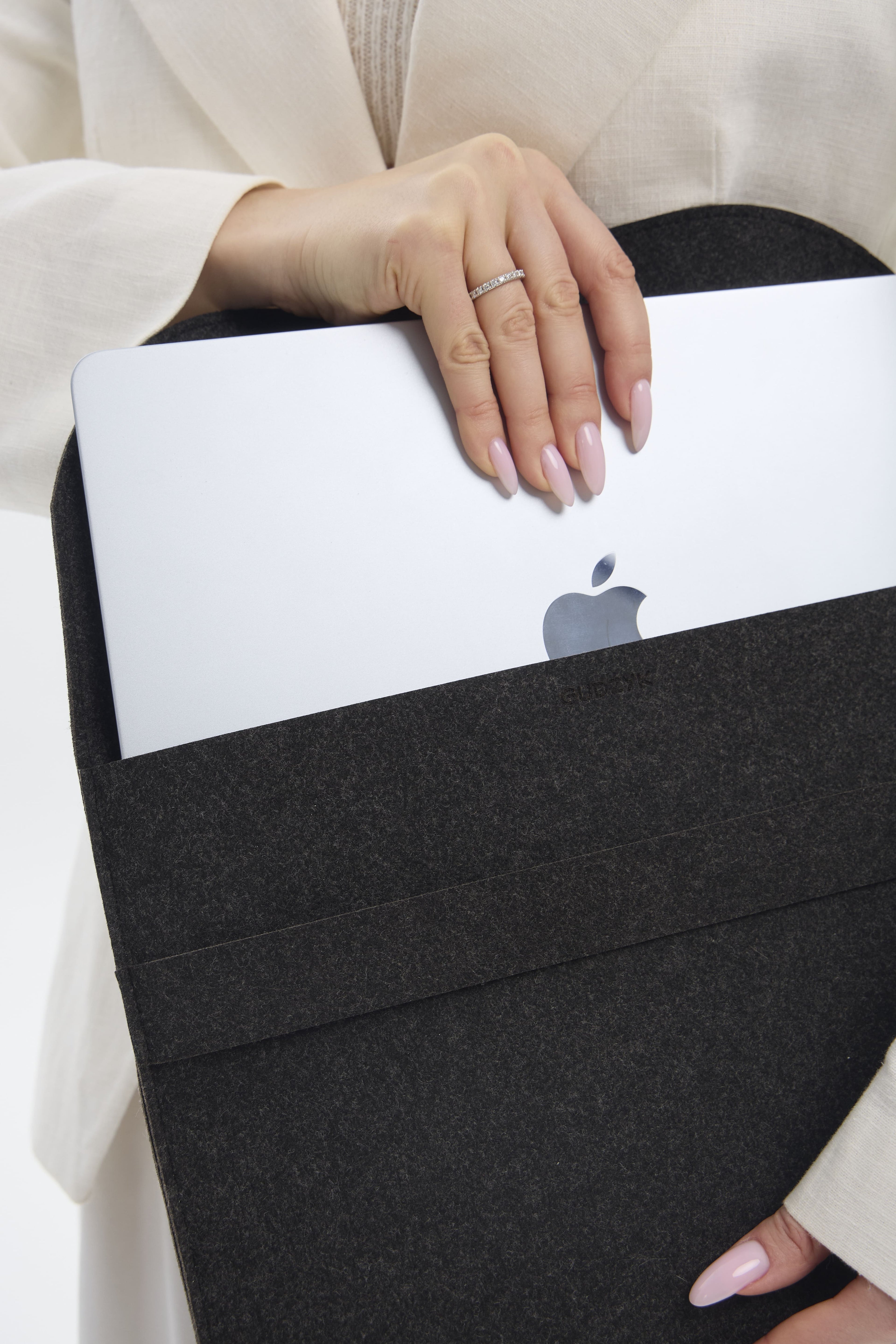 Person holding a black laptop sleeve with an Apple logo on a white background