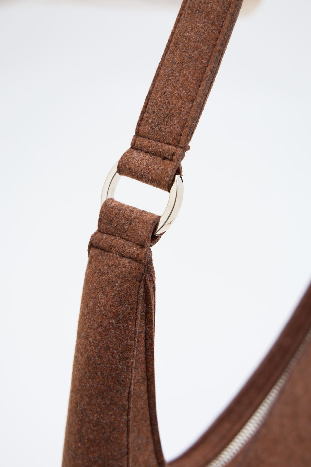 Close-up of a brown ecofelt strap with a metal buckle on a white background