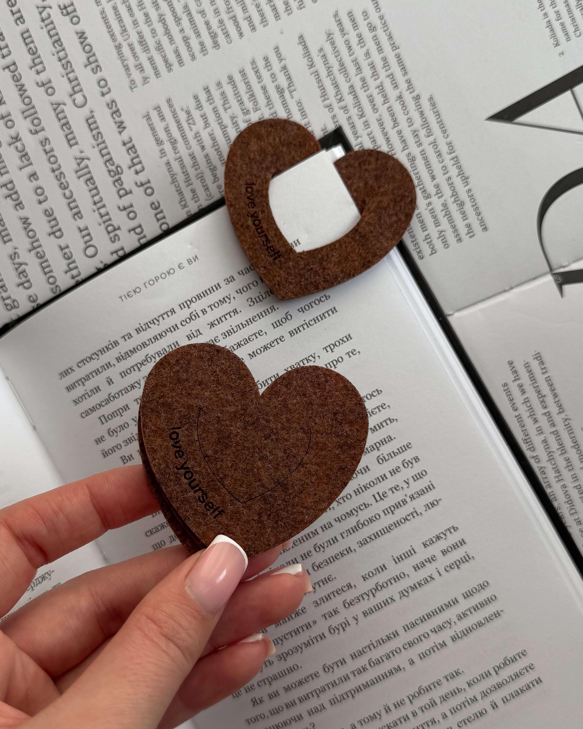 Heart-shaped brown felt bookmark with a white center on an open book.