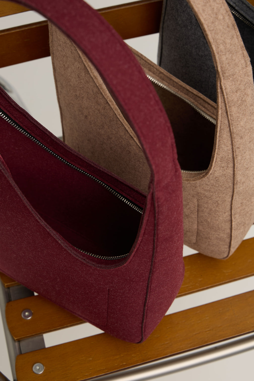 Two handbags, one burgundy and one beige, on a wooden surface.