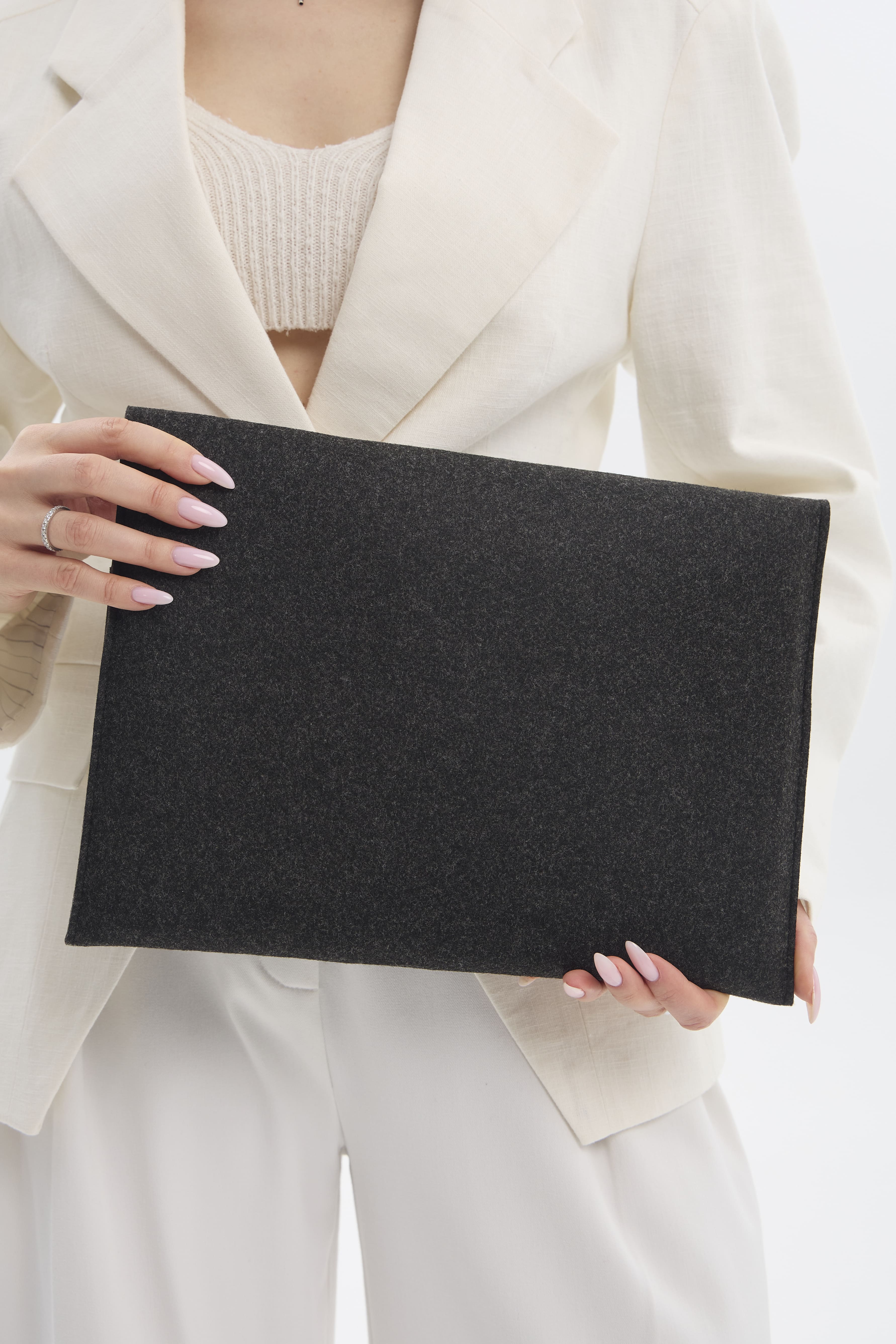 Person holding a black  case for macbook against a white background