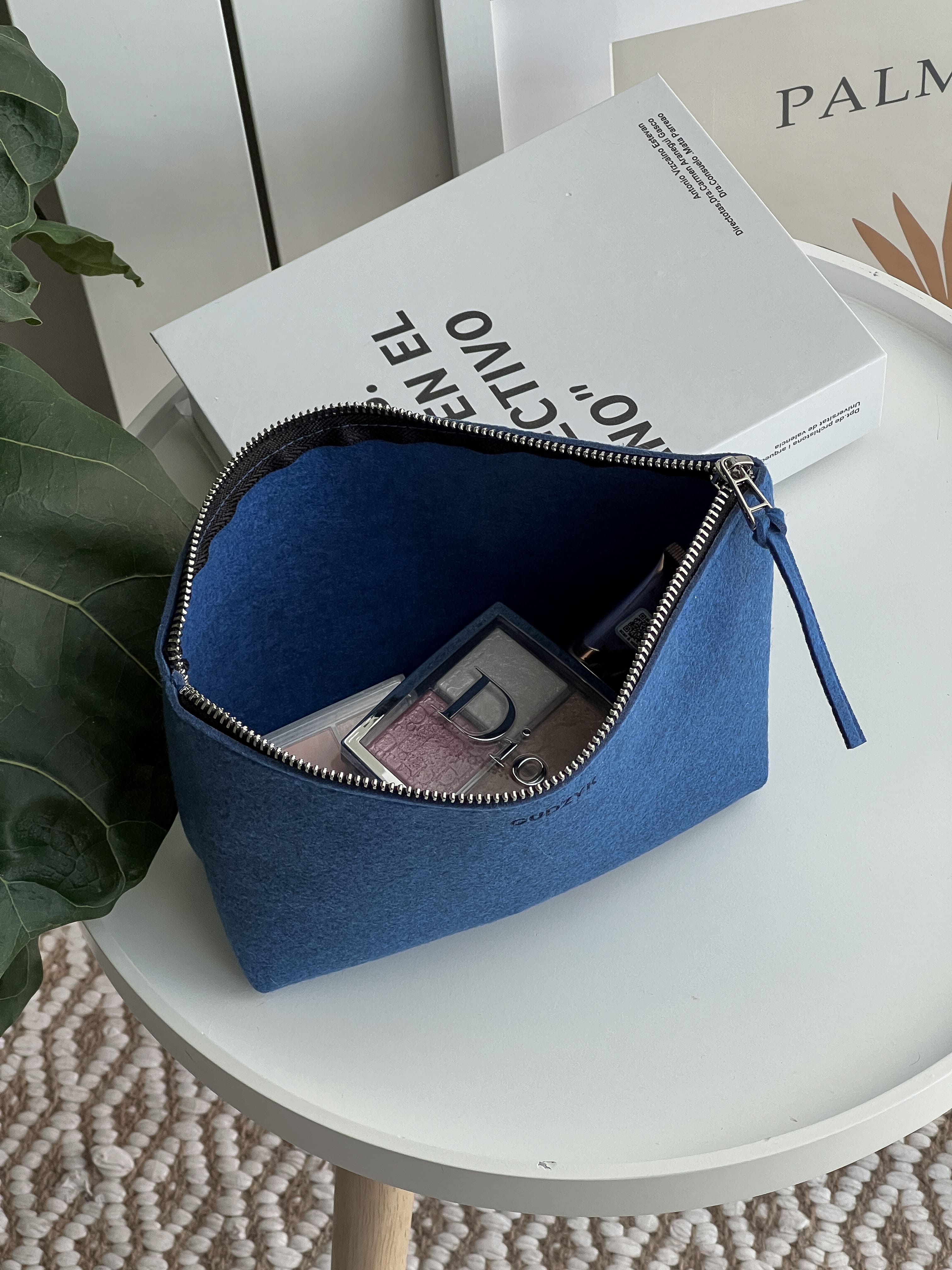 dark blue pouch on a white surface with books in the background