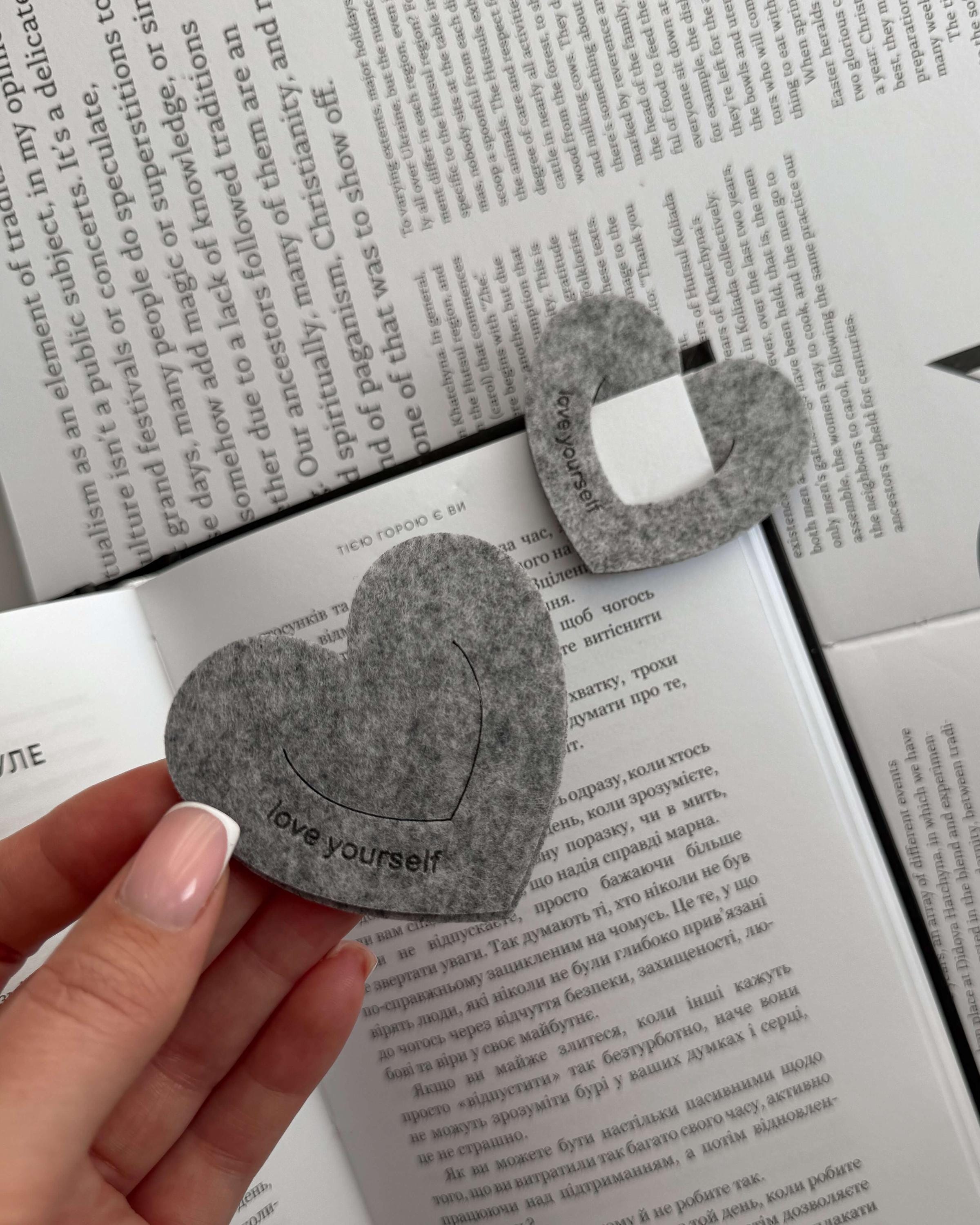Heart-shaped gray bookmark with 'love yourself' text on an open book.
