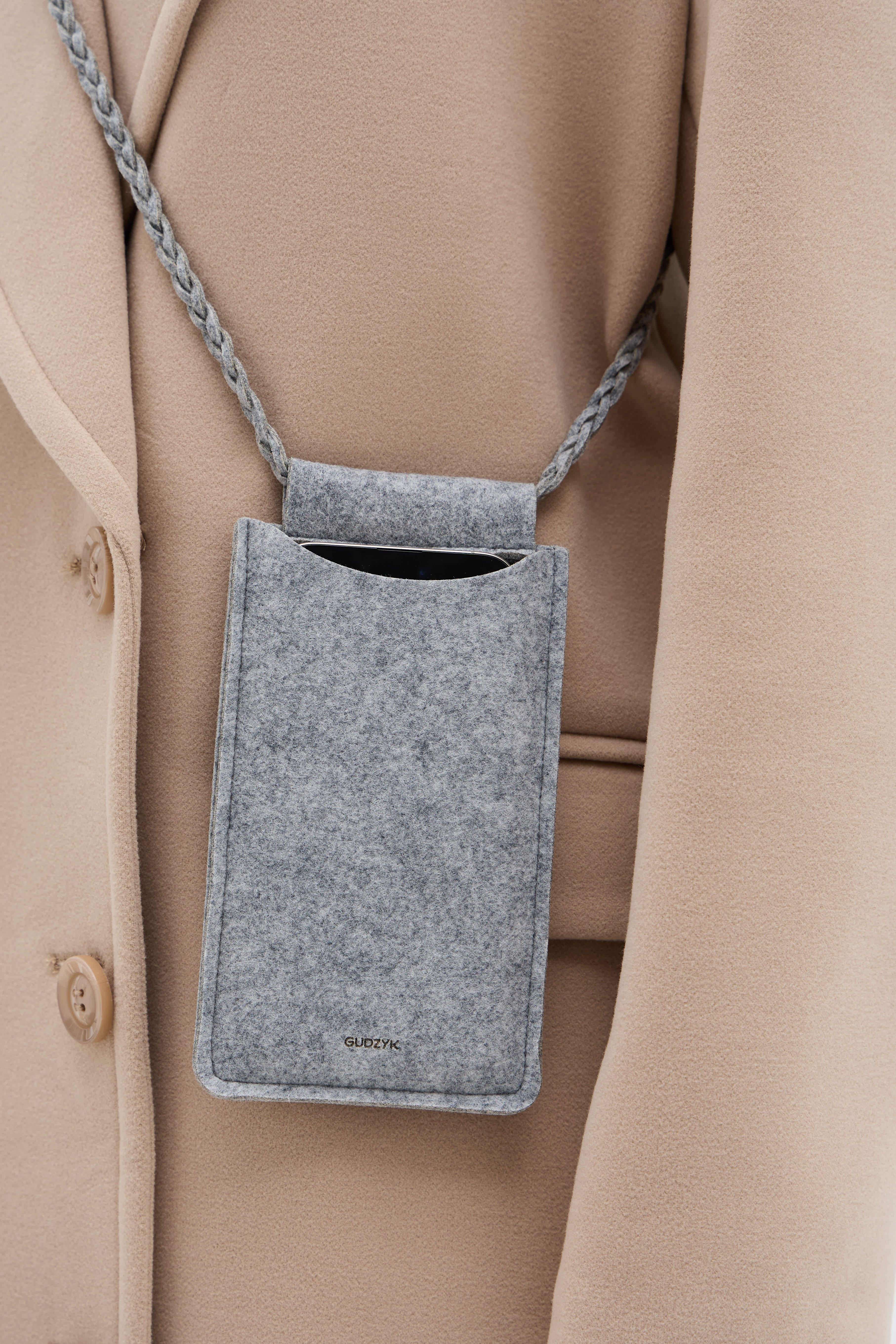 gray crossbody bag with a braided strap worn with a beige coat