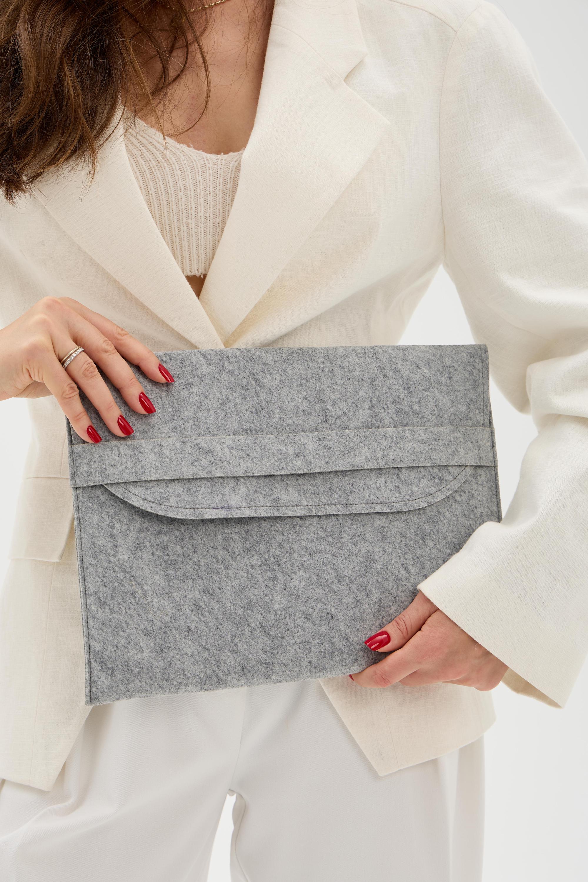 Person holding a gray laptop sleeve against a white background