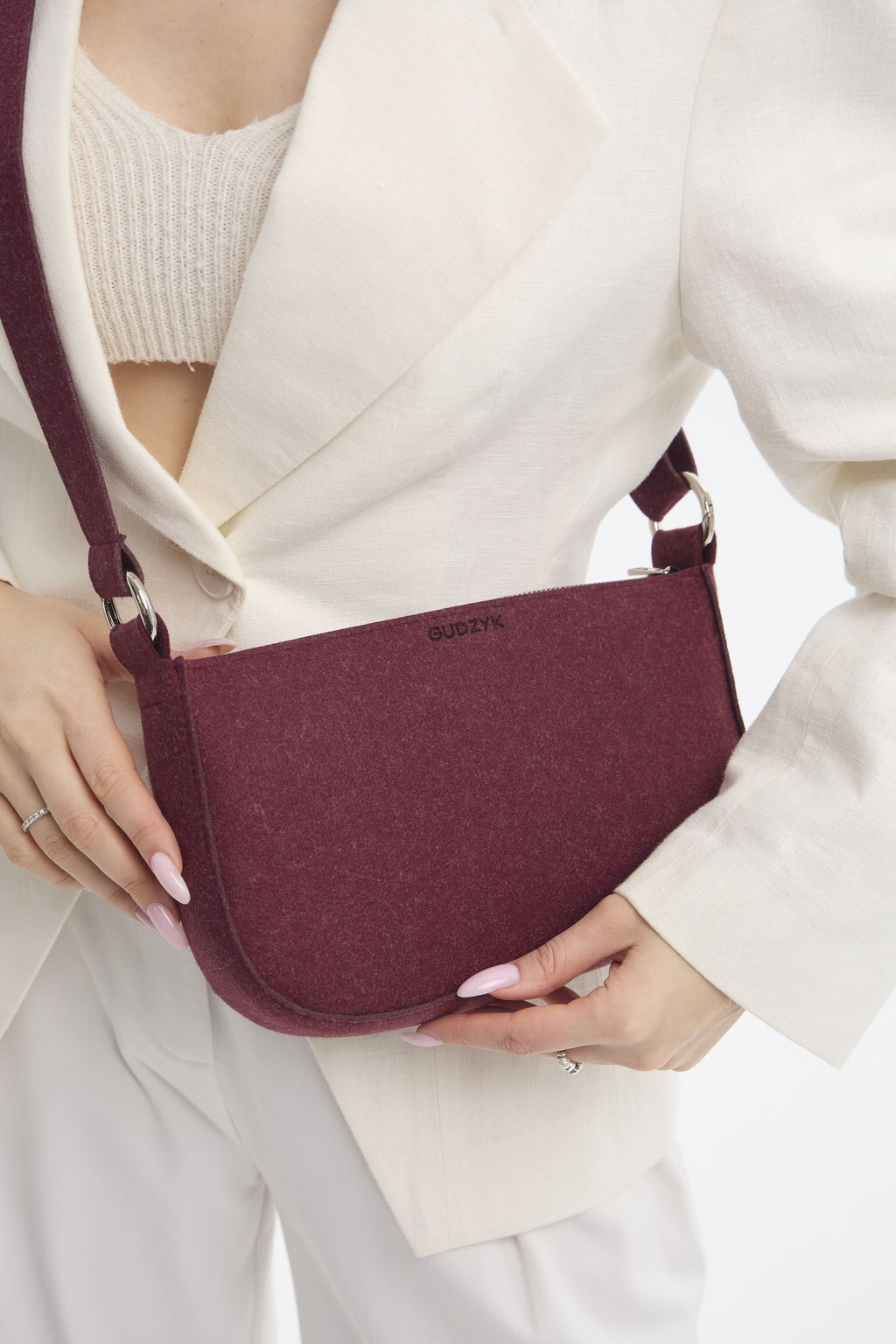 Person holding a maroon handbag with a blurred background