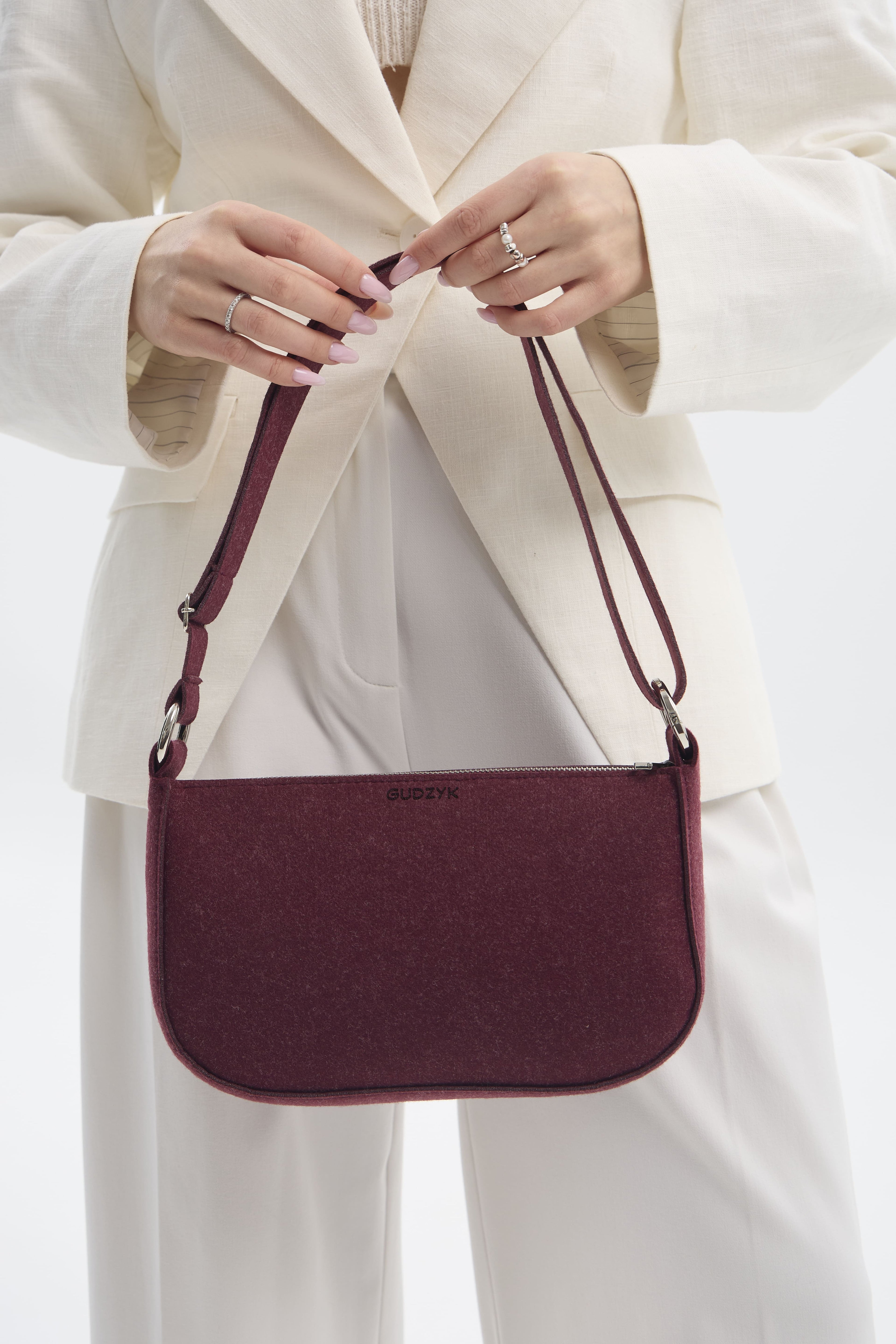 Person holding a maroon handbag with a white background