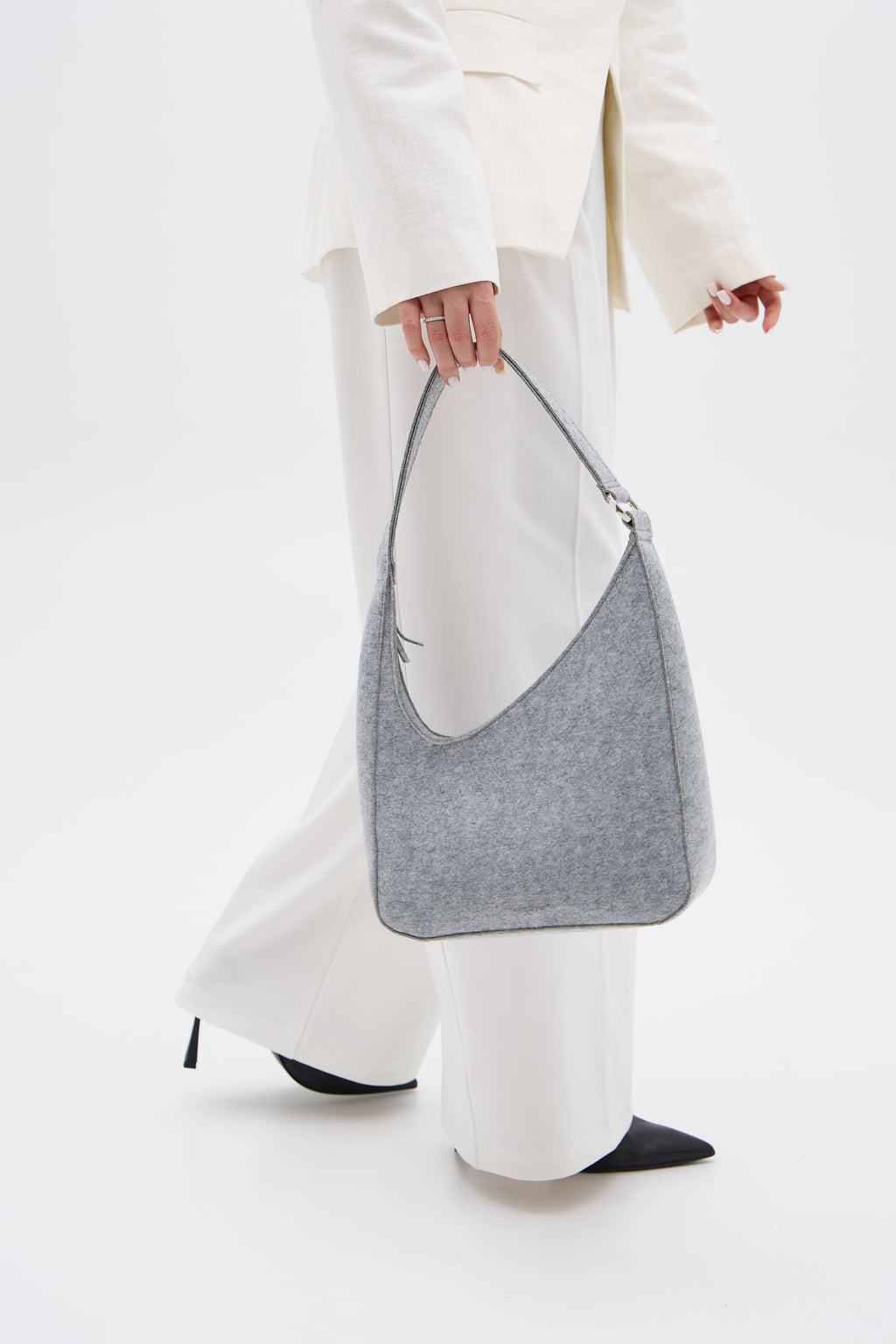 Person holding a silver gray shoulder bag against a white background